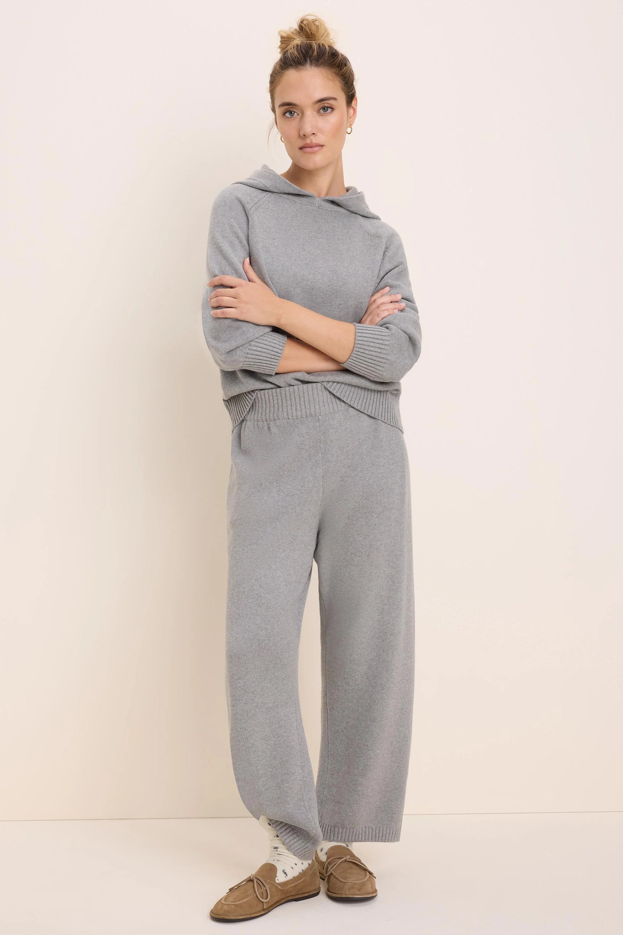 Model wears light grey Billie Sweater Pants, wide-leg, relaxed fit, paired with a matching grey hooded top.