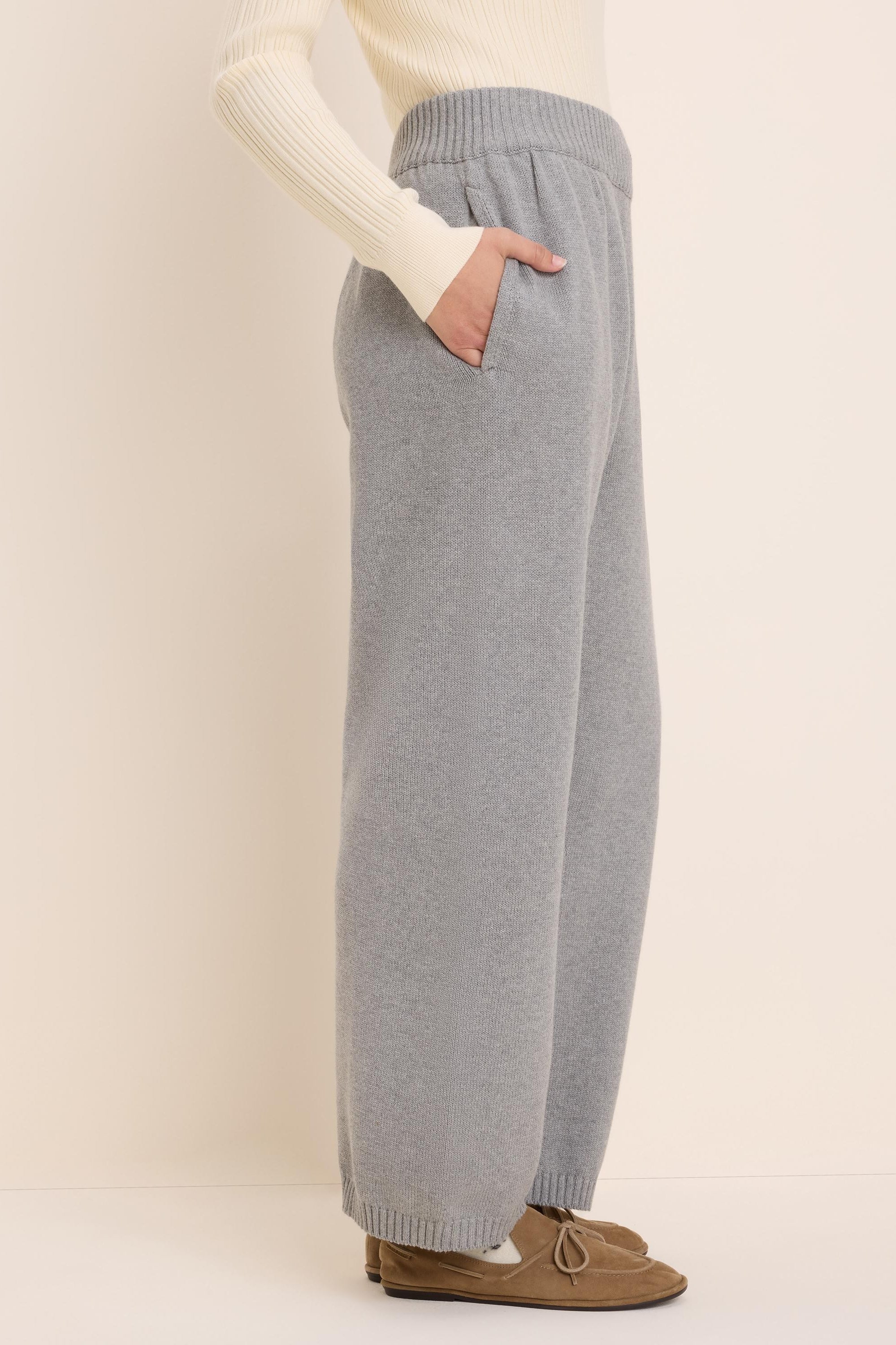 Light grey knit sweater pants with a ribbed elastic waist, side pockets, and wide legs with ribbed cuffs.