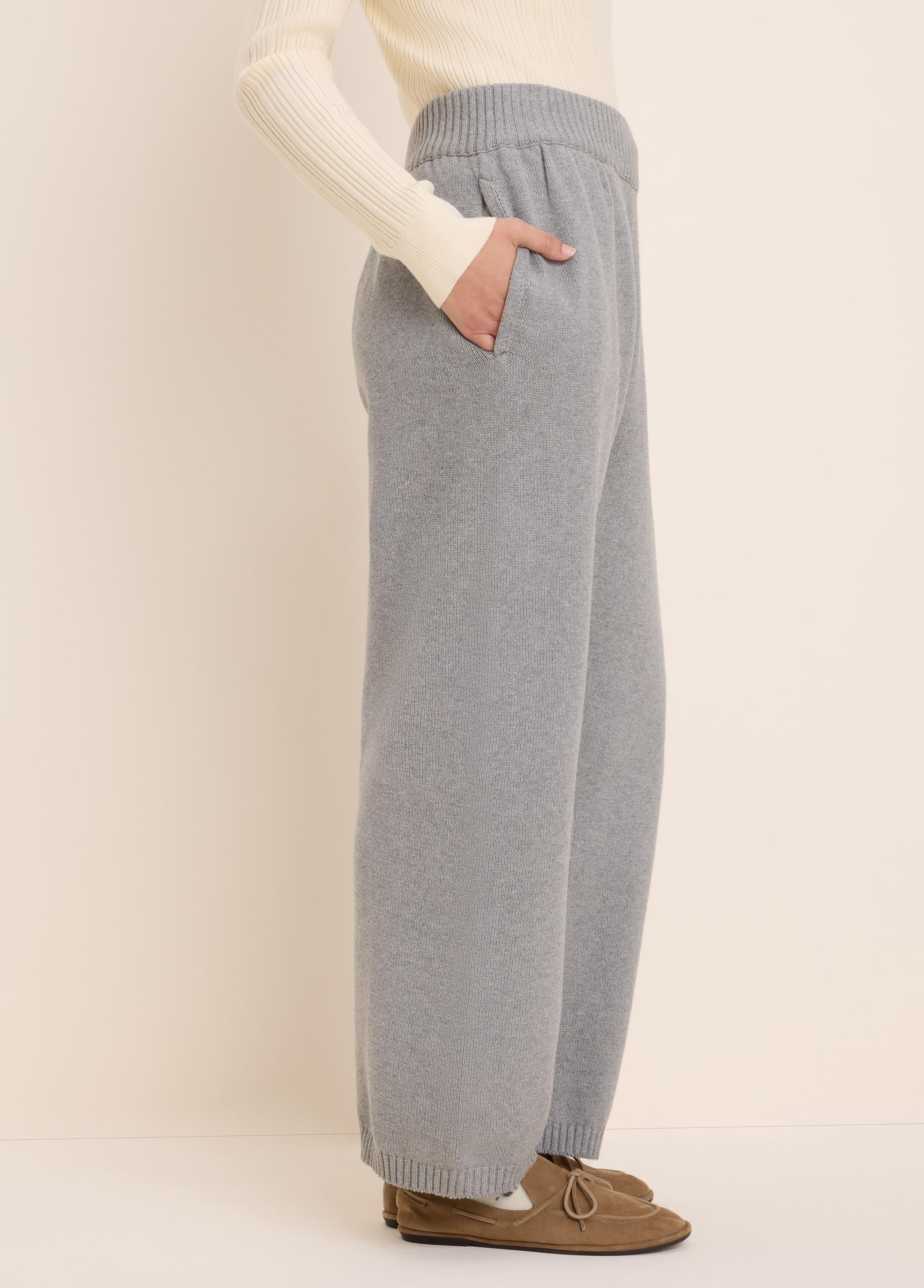 Light grey knit sweater pants with a ribbed elastic waist, side pockets, and wide legs with ribbed cuffs.
