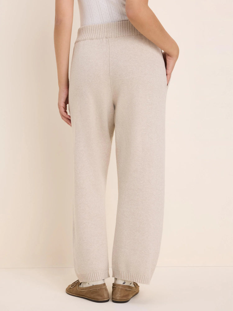 Light beige wide-leg knit pants with ribbed waistband and cuffs, shown from the back.