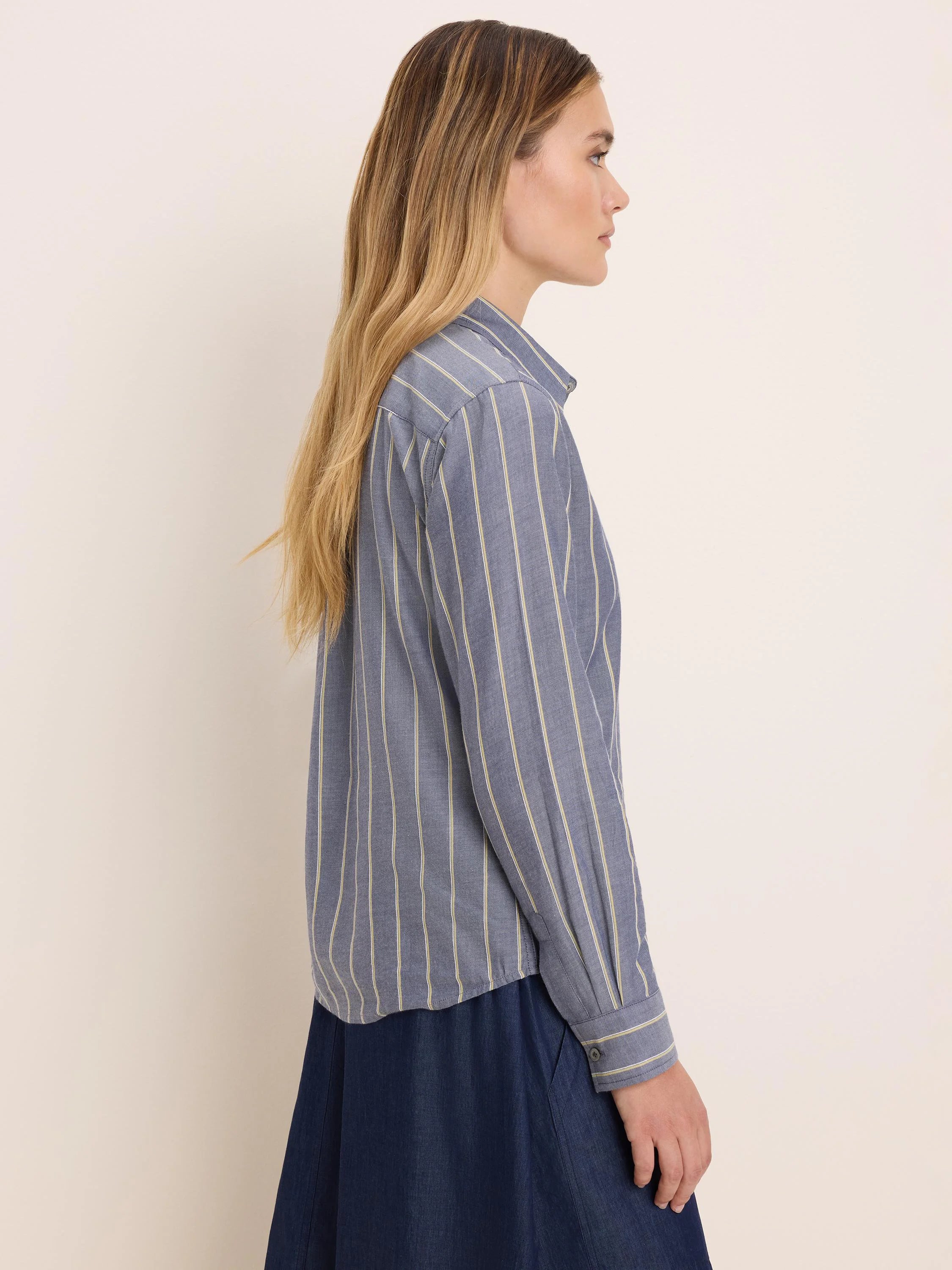 Muted blue dobby stripe shirt with pale yellow vertical stripes, worn by a model in profile.