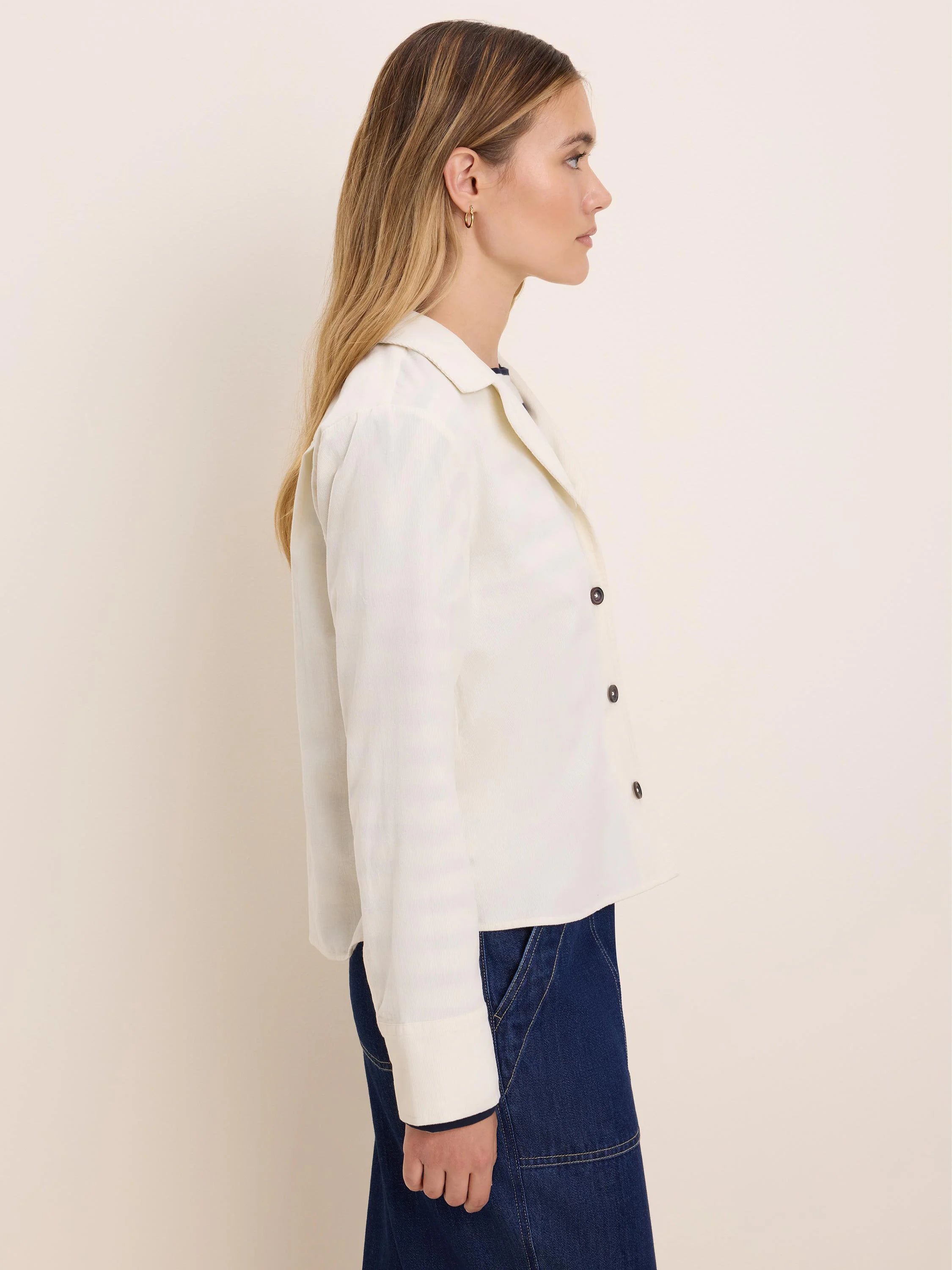 Off-white baby corduroy shirt jacket with a collar, dark buttons, and cuffed long sleeves.
