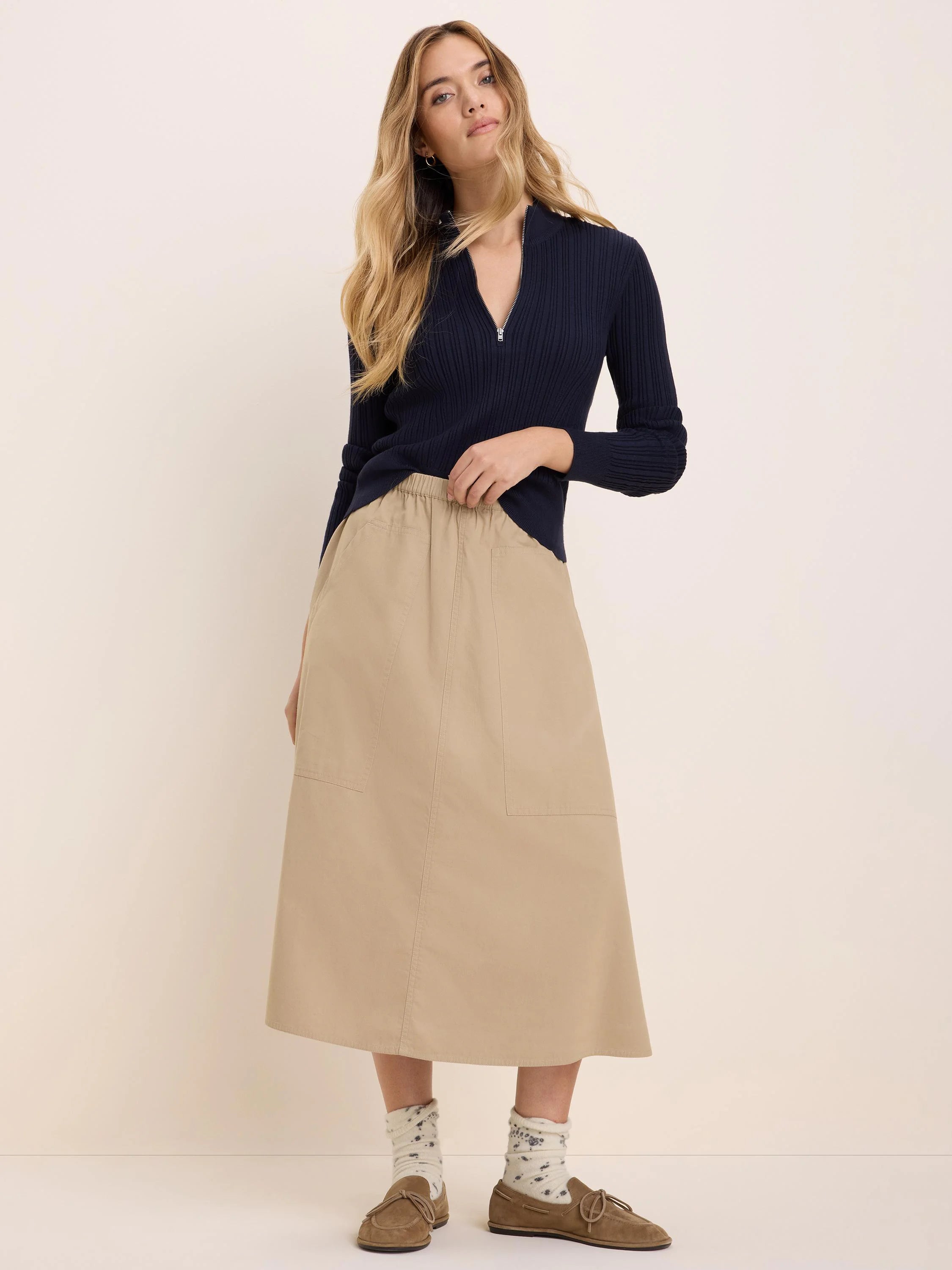 Beige twill cargo skirt with elastic waist, front patch pockets, and midi length.
