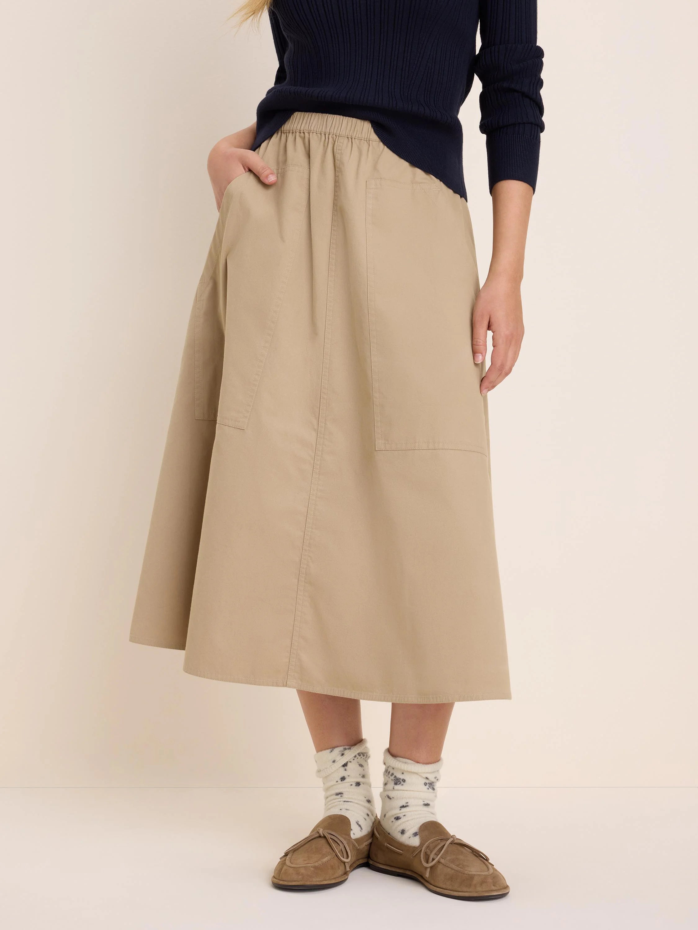 Khaki twill cargo skirt with elastic waist, midi-length, and large front patch pockets.