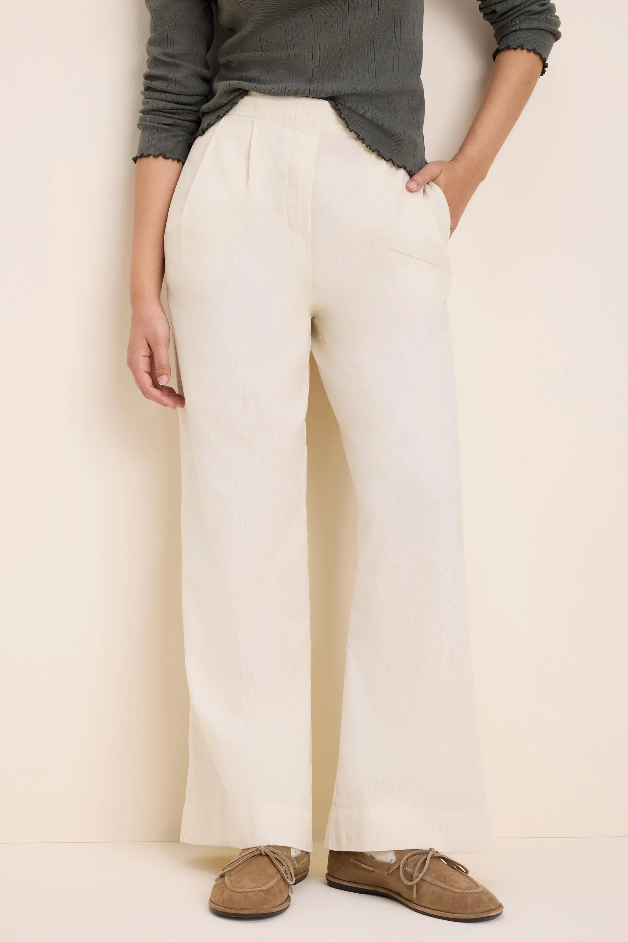 Cream baby corduroy pants, high-waisted with front pleats and wide legs.