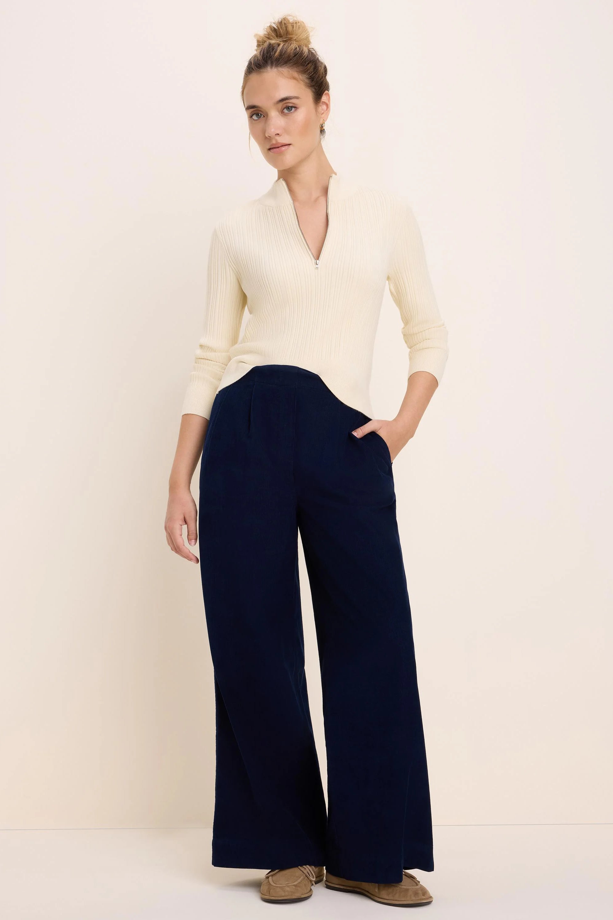 Navy blue baby cord wide-leg pants with front pleats, worn by a model.