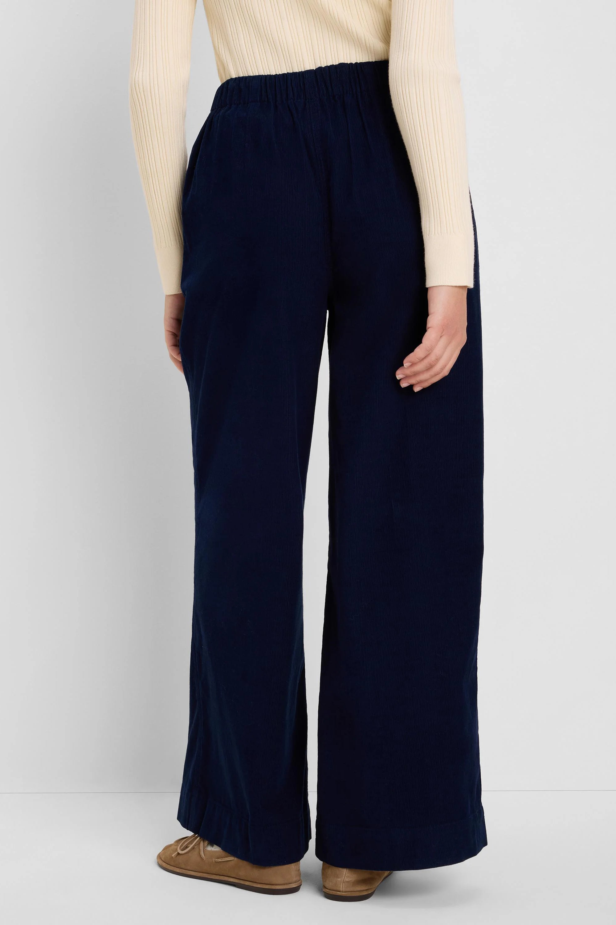 Navy blue baby cord pants with wide legs and an elasticated waist, shown from behind.