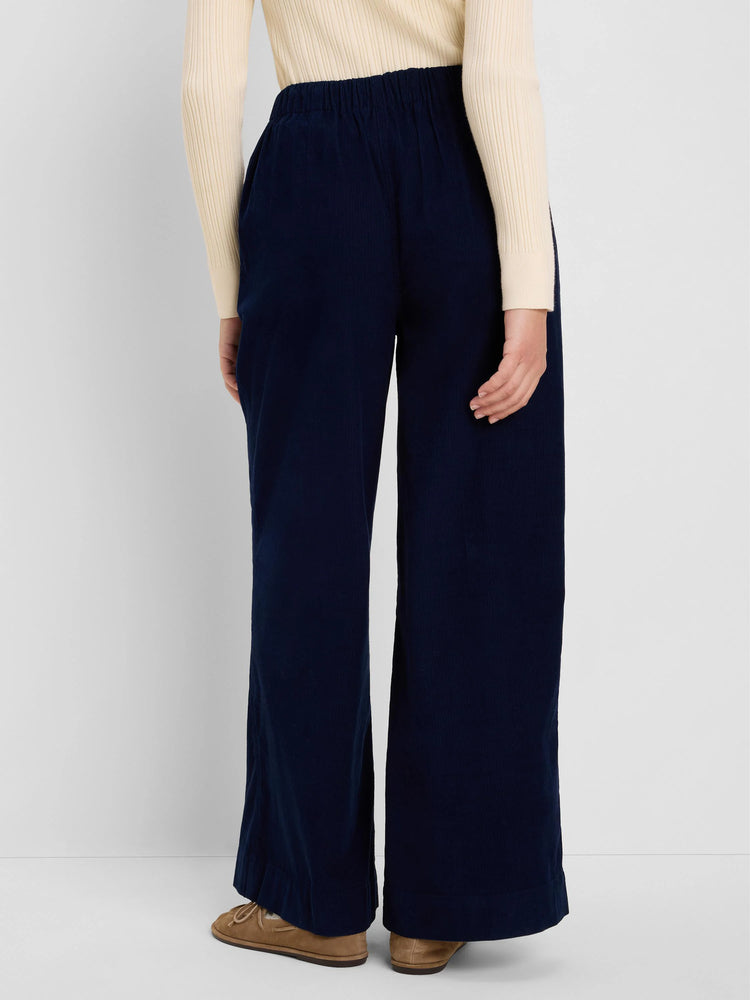 Navy blue baby cord pants with wide legs and an elasticated waist, shown from behind.
