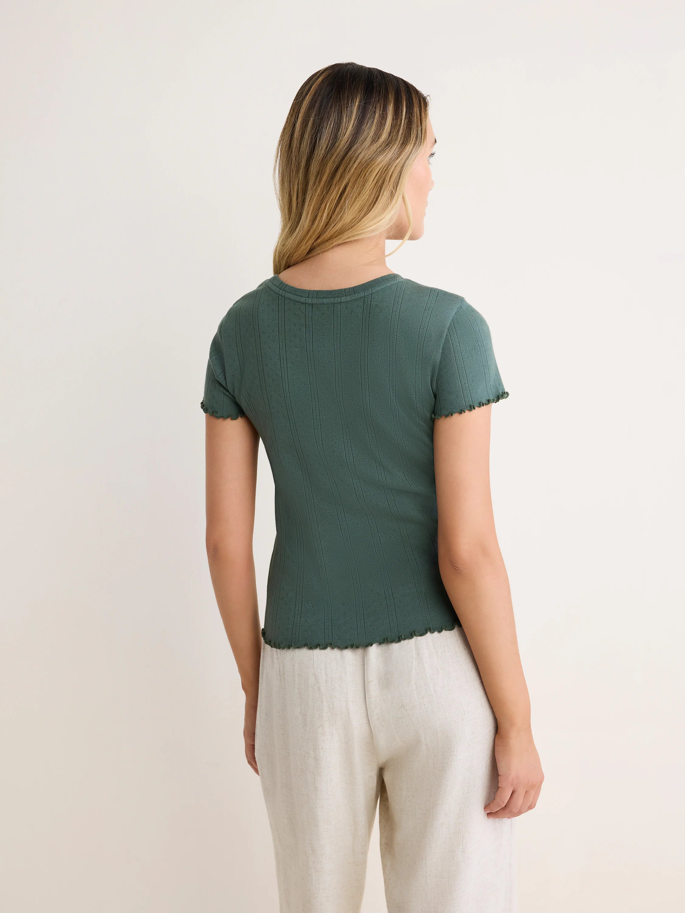 Dark green pointelle rib tee with short sleeves and ruffled edges on sleeves and hem.