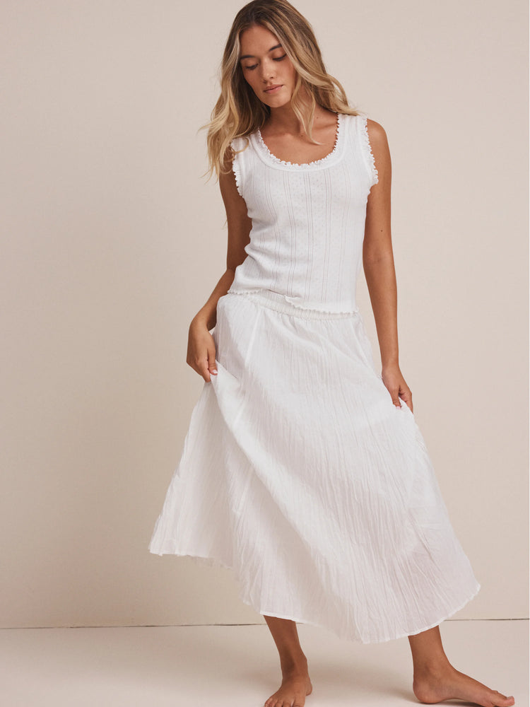 White pointelle rib knit tank top with ruffled trim on the round neckline and armholes.