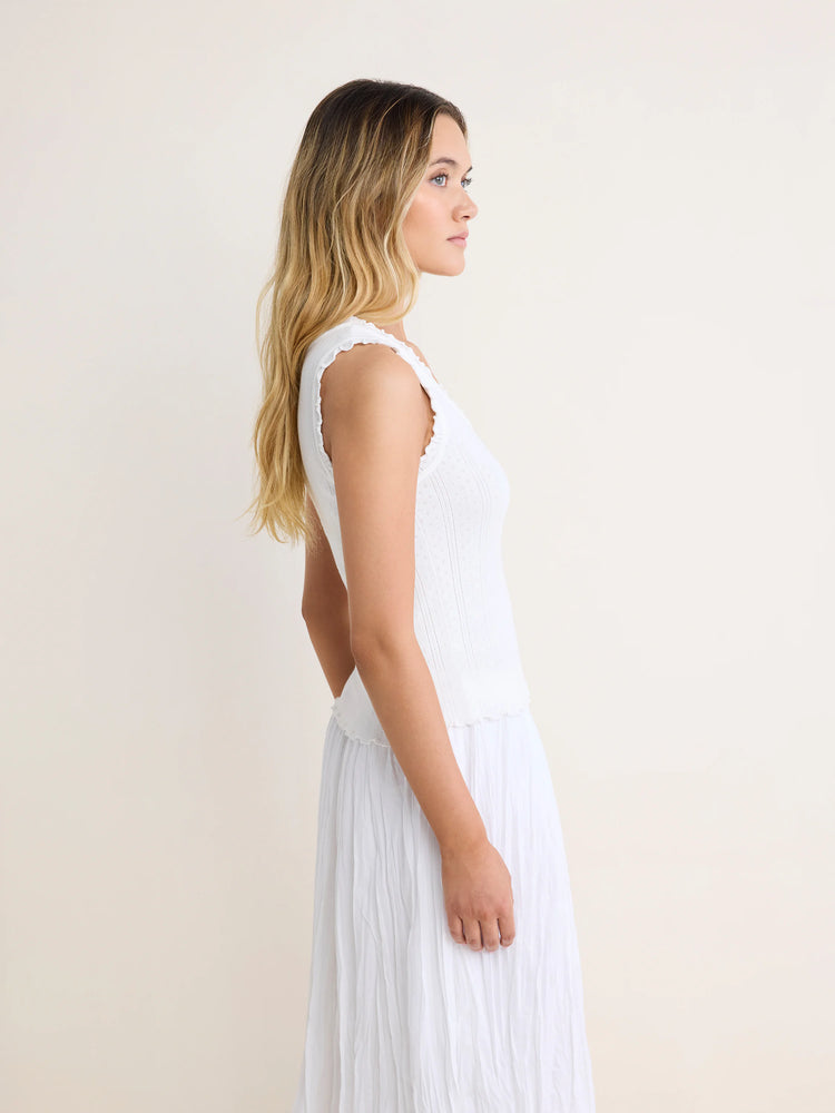 White pointelle ribbed tank top with ruffled neckline and armholes.