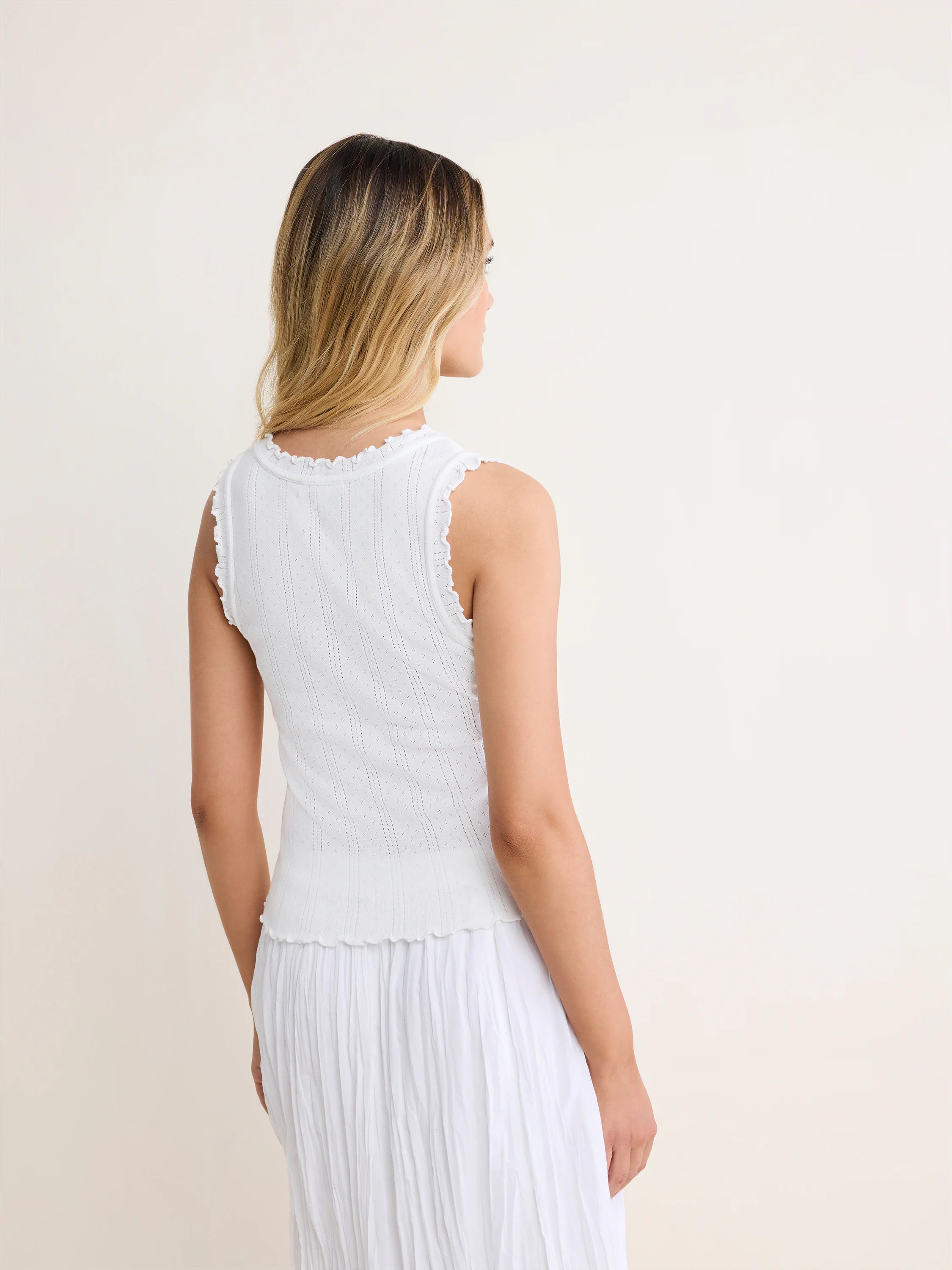 White pointelle rib tank top with scalloped neckline, armholes, and hem shown from the back.