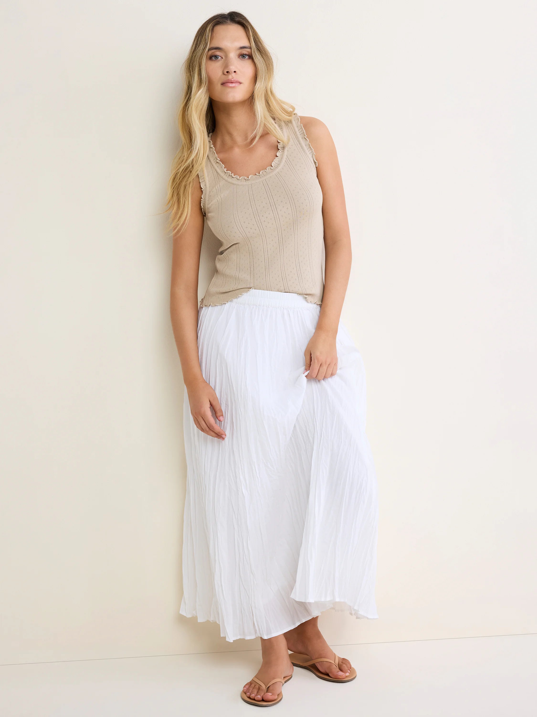 Beige pointelle rib tank with ruffled neckline, armholes, and hem.