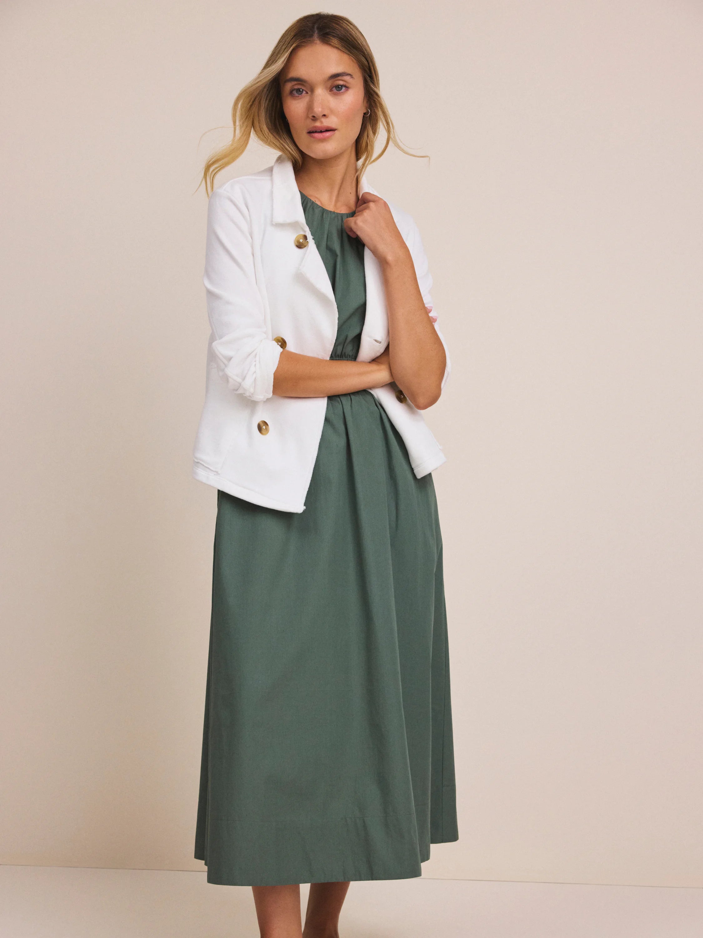 White jacket with blazer-style lapels, large round brown buttons, and rolled sleeves.