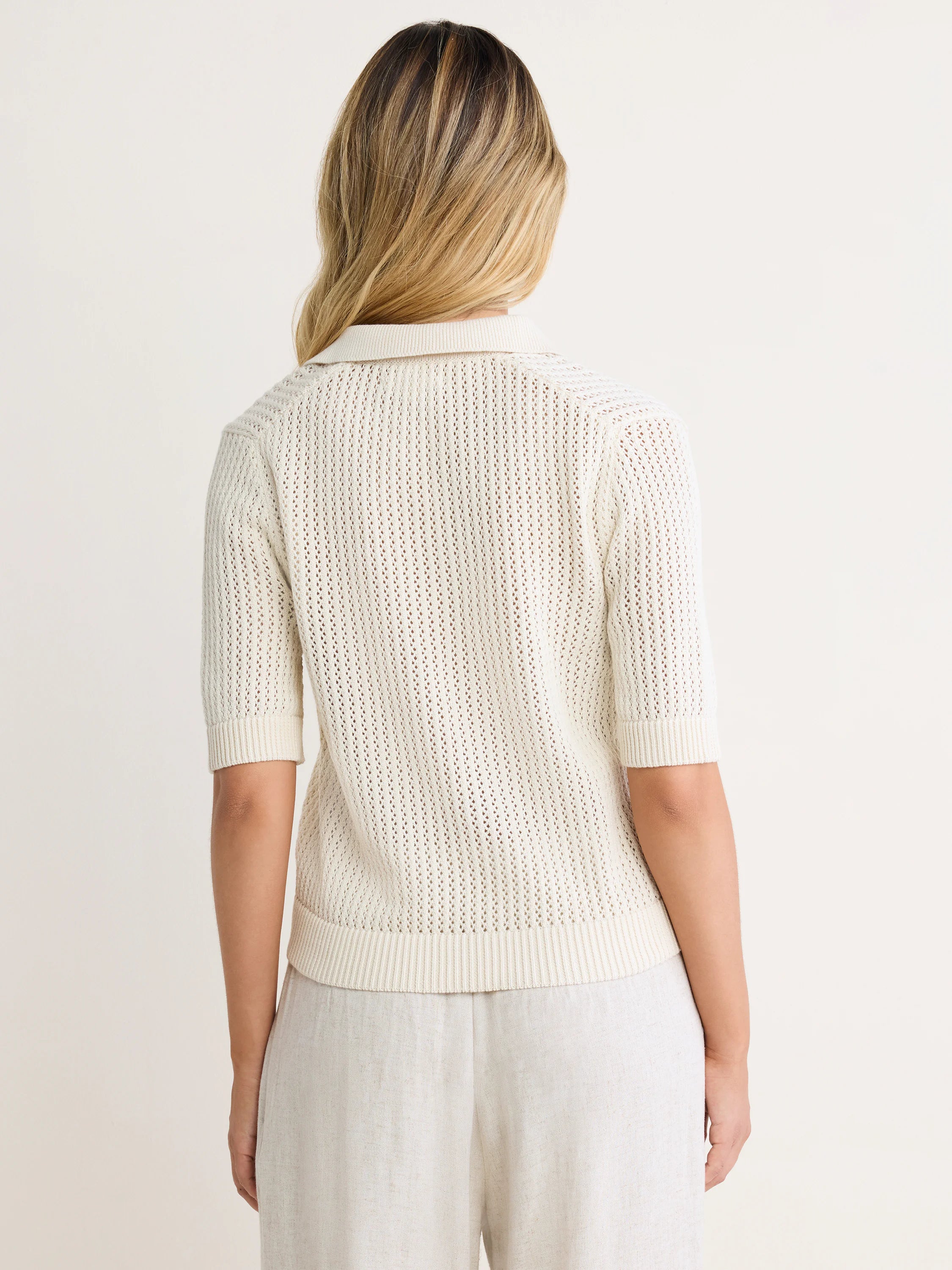 Off-white mesh polo sweater with short sleeves, ribbed collar, cuffs, and hem. Model shown from the back.