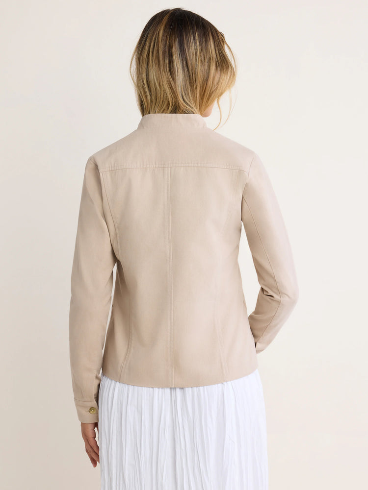 Back view of a light beige cotton twill jacket. It has a stand collar, shoulder yoke, vertical back seams, and button cuffs.