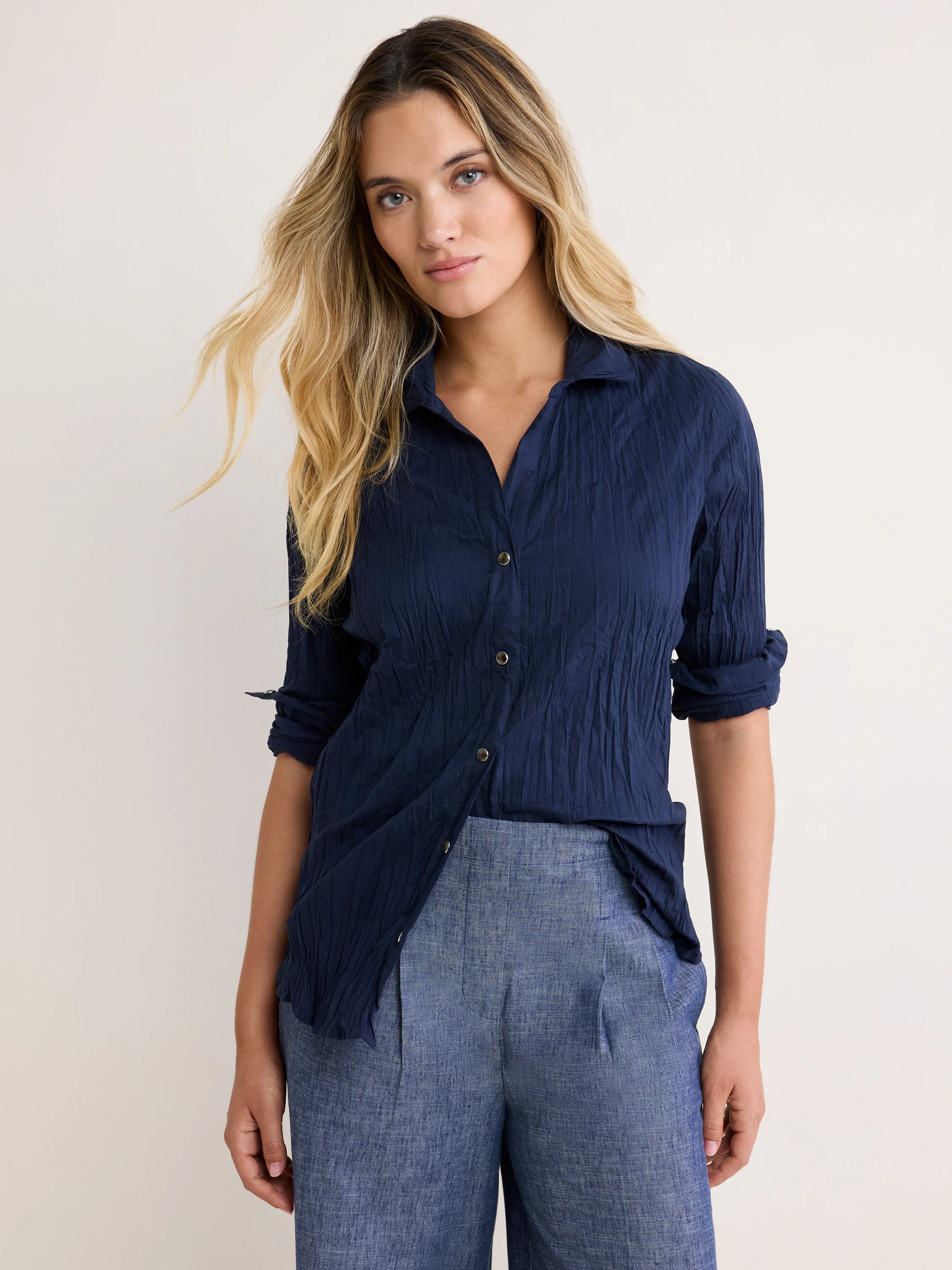 Navy blue crinkled cotton shirt with a collar, button-front closure, and rolled sleeves.