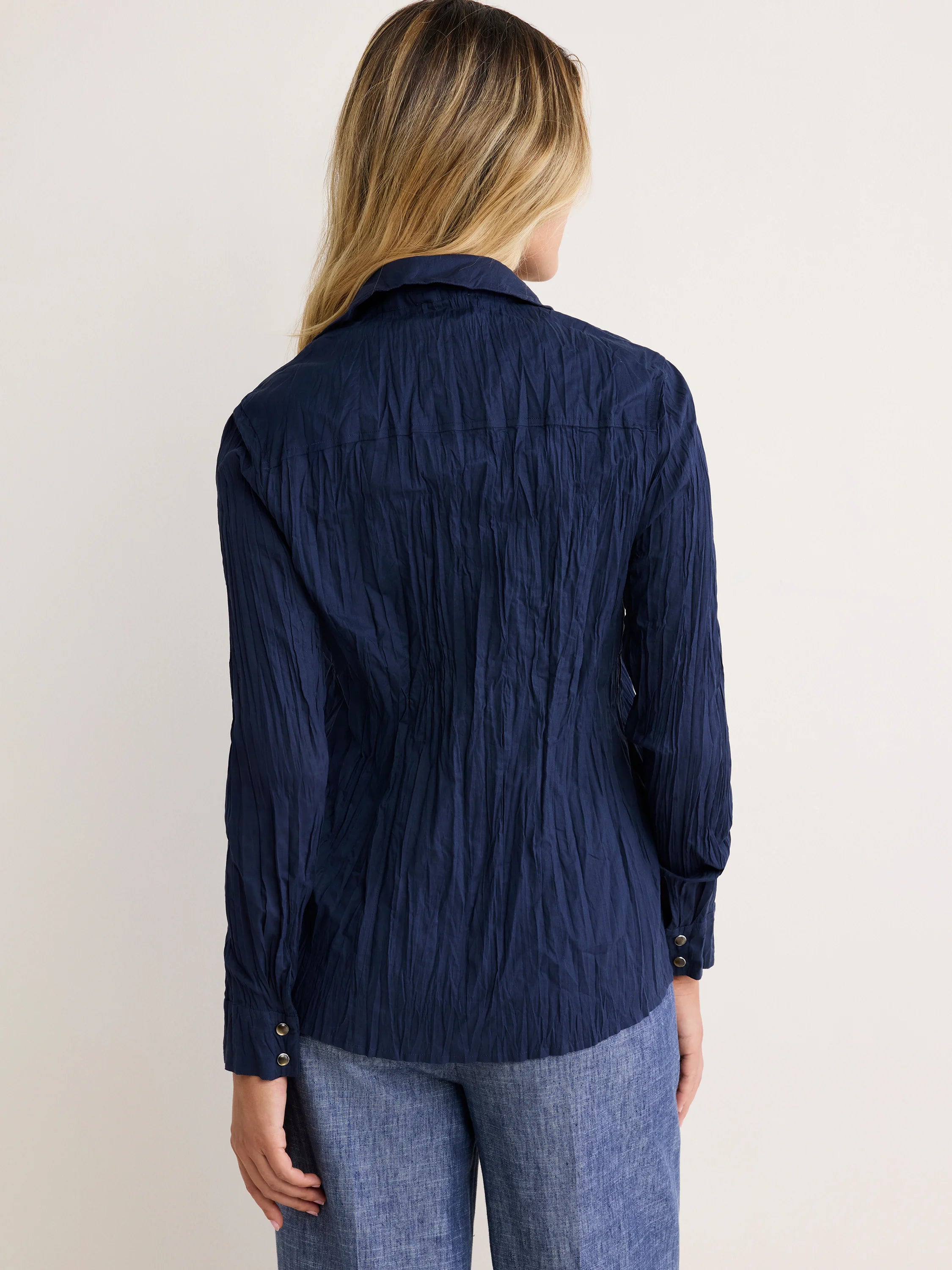 Dark navy blue crinkled cotton shirt, shown from behind, with long sleeves and buttoned cuffs.