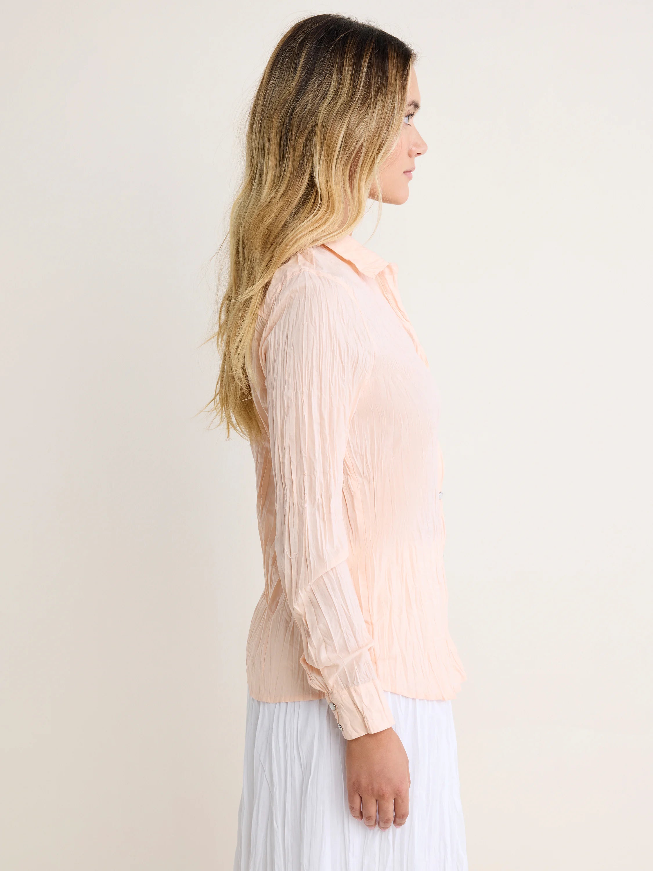 Blush crinkled shirt with long sleeves, collar, and front buttons.