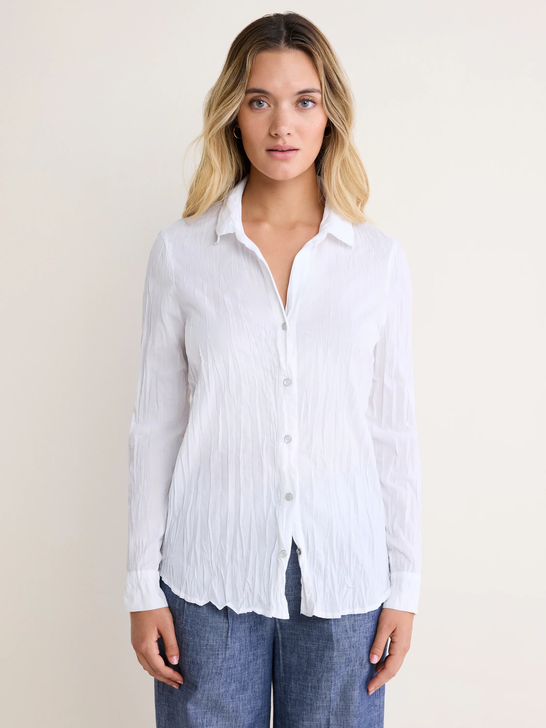 White, crinkled long-sleeved shirt with a collar and front button closure.