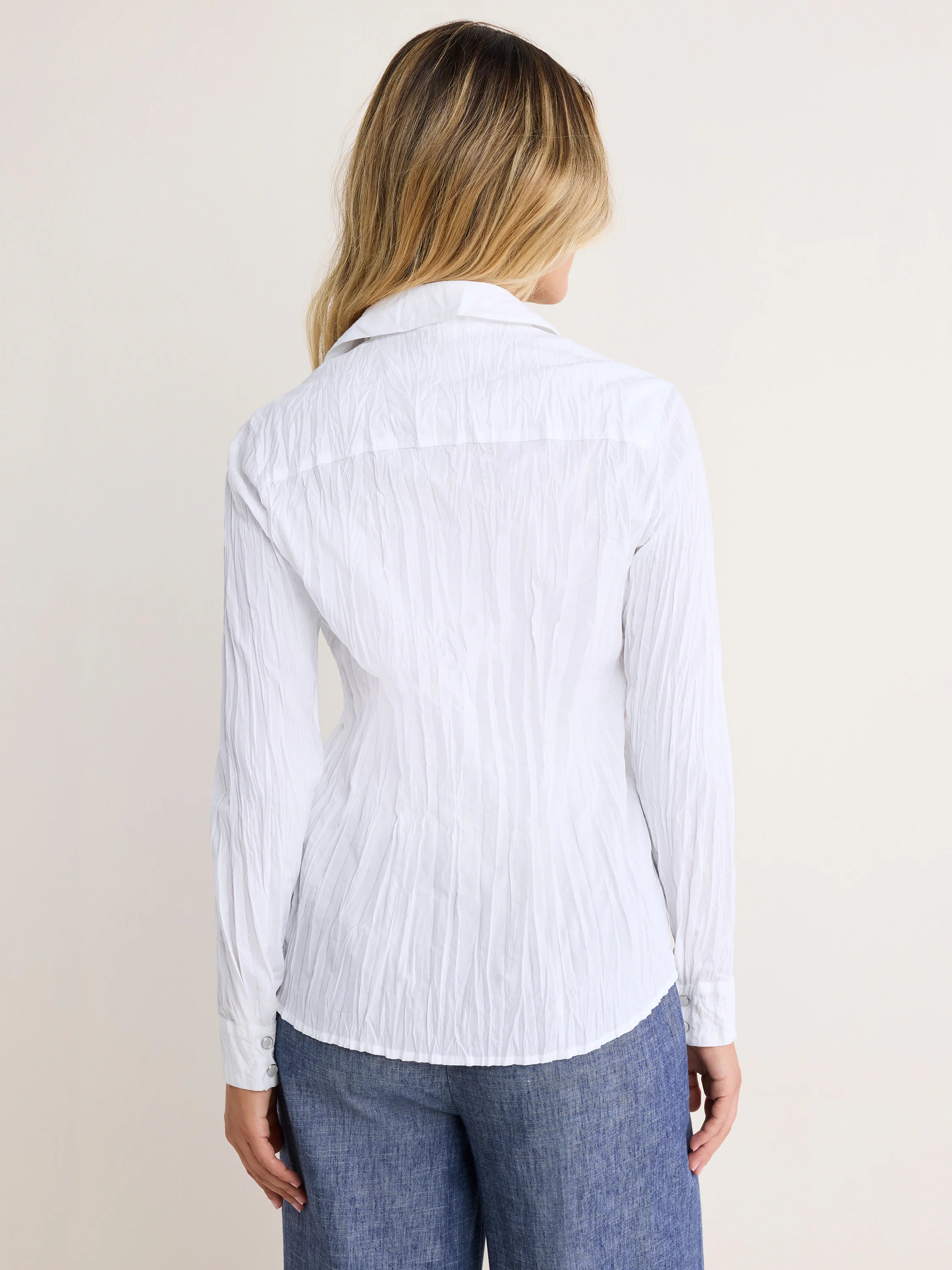 White crinkled long-sleeve shirt, back view. Features two silver cuff buttons.
