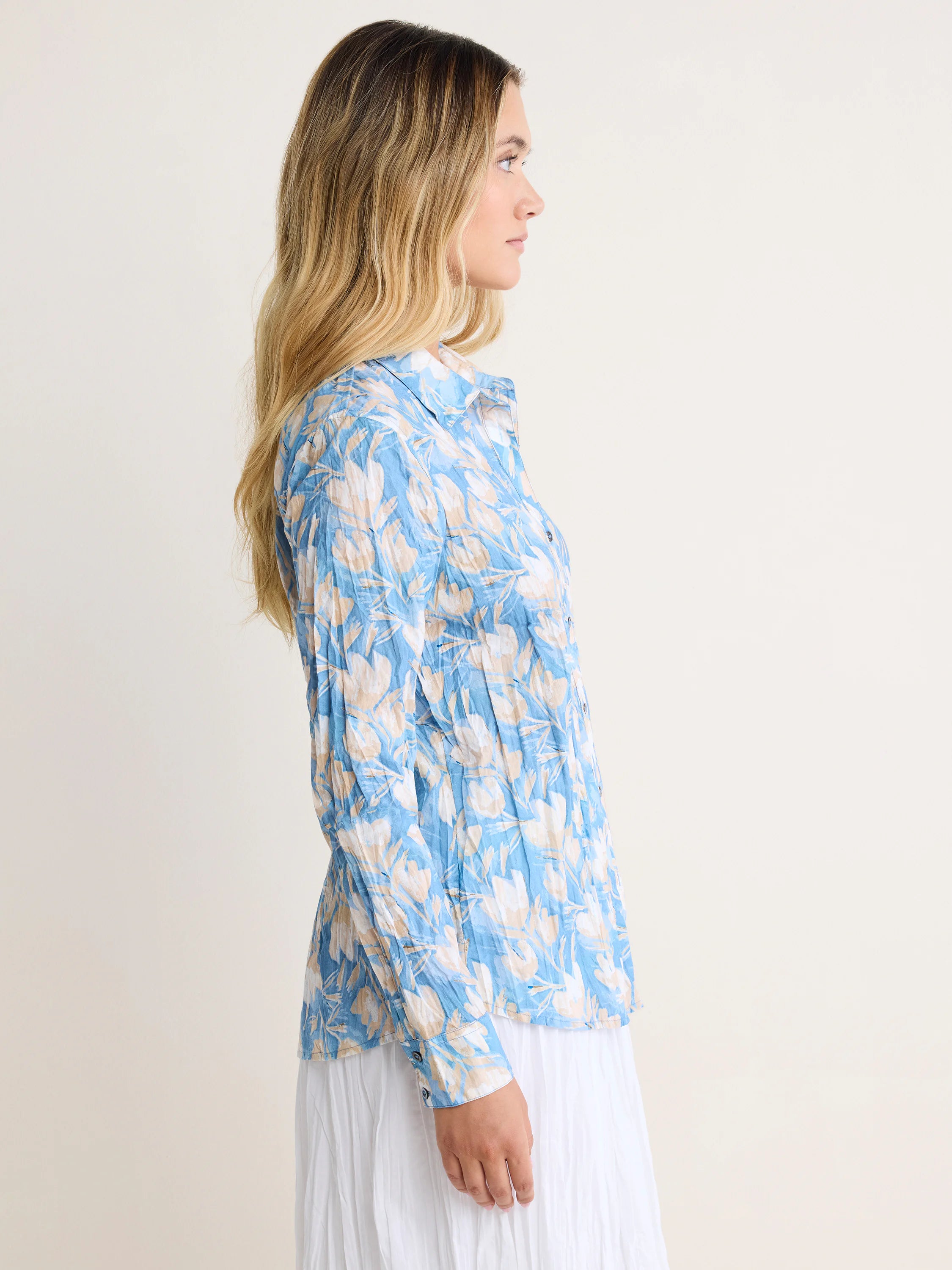 Crinkled blue button-up shirt with light beige and white floral print, long sleeves.