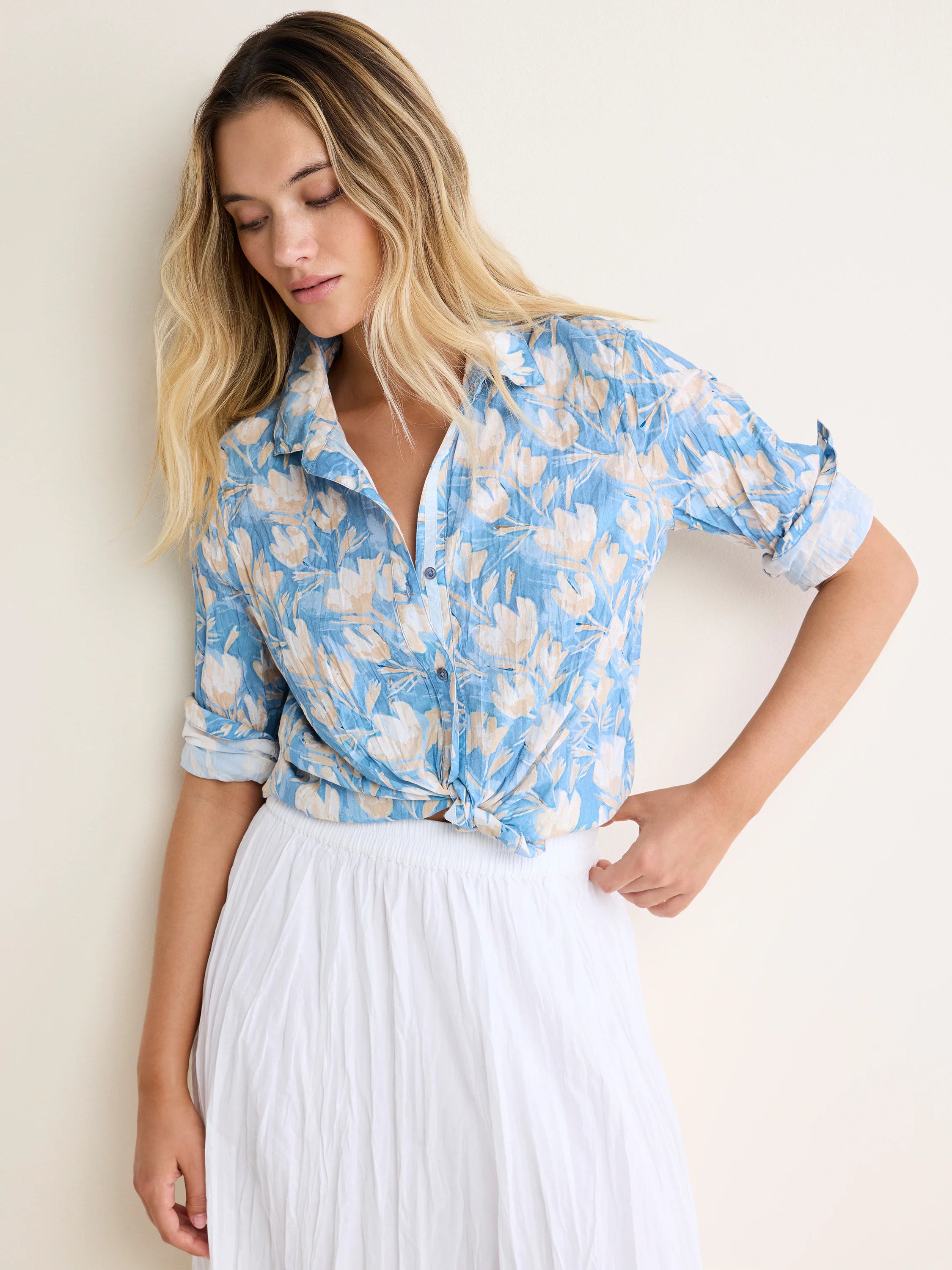 Light blue shirt with cream floral pattern, rolled sleeves, tied at waist. Crinkled fabric.
