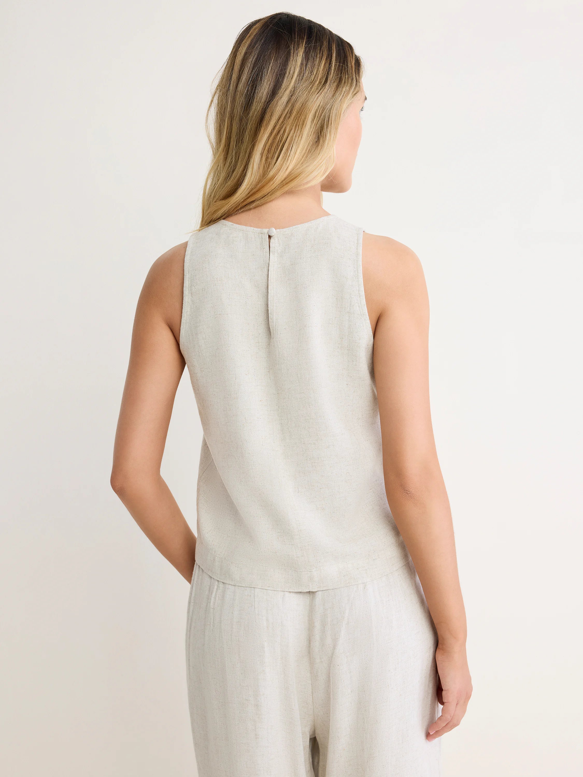 Light beige linen blend sleeveless tank. Keyhole button closure at back neck on model, seen from behind.