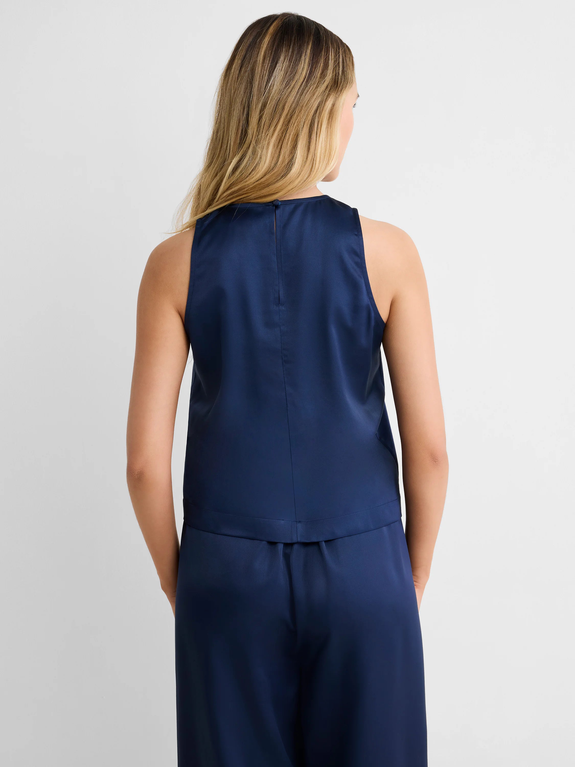 Navy blue sleeveless tank top on a woman from behind, featuring a high neck, keyhole button closure, and a subtle sheen.