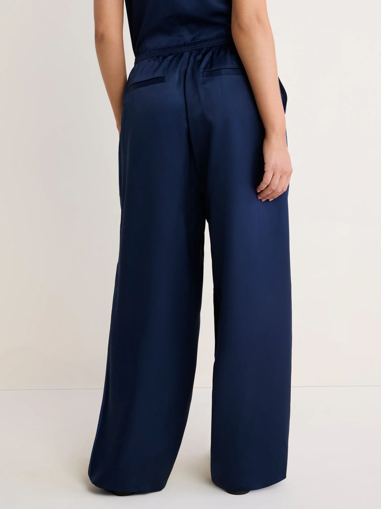 Rear view: Dark navy wide-leg pants with satin sheen, elasticized rear waist, two horizontal back pockets.