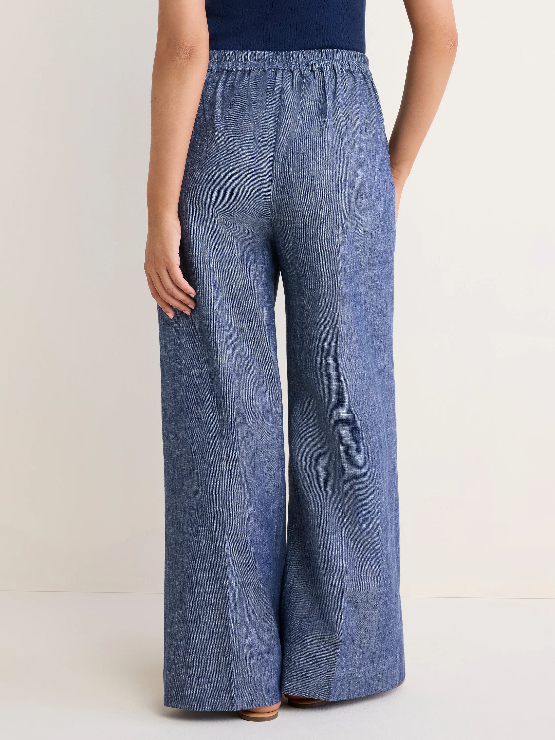 Back view of loose, textured blue wide-leg trousers with an elastic waist.