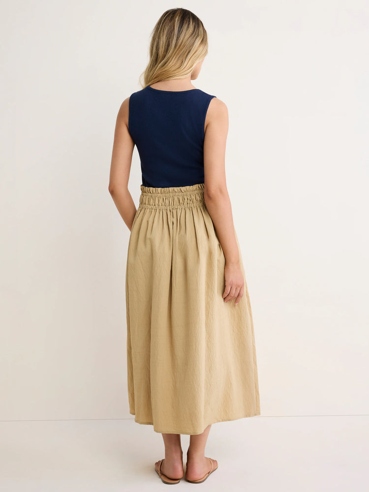 Navy sleeveless dress with a tan crinkled midi skirt and gathered elastic waist. Model from back.