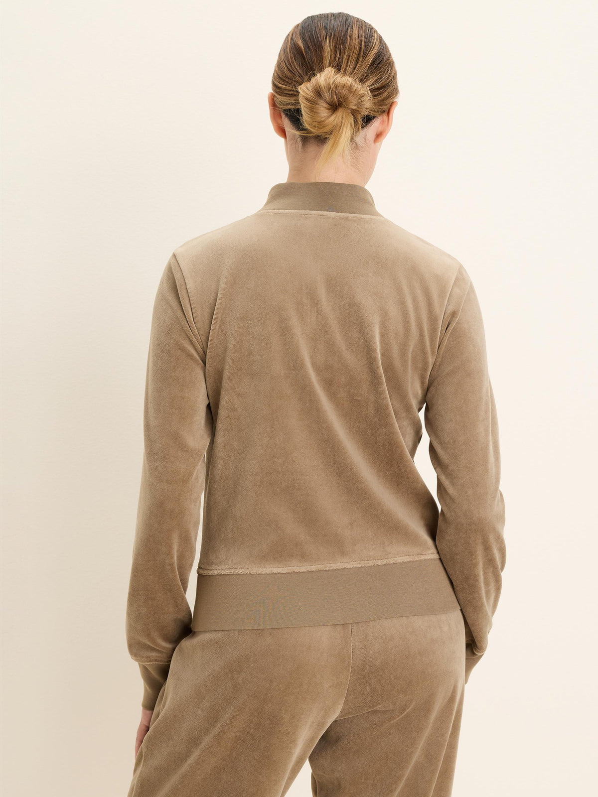 Back view of a camel velour pullover with a high stand-up collar and a ribbed hem.