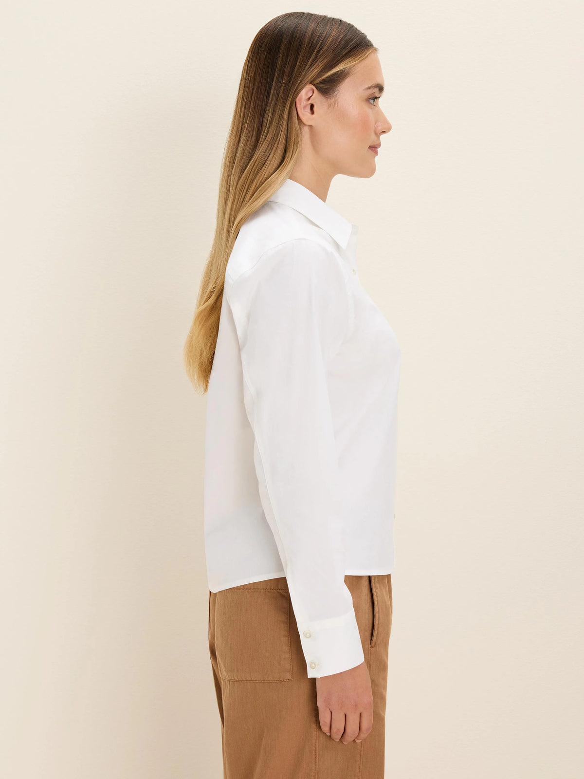 White collared long-sleeve shirt with buttoned cuffs, worn by a model in profile.