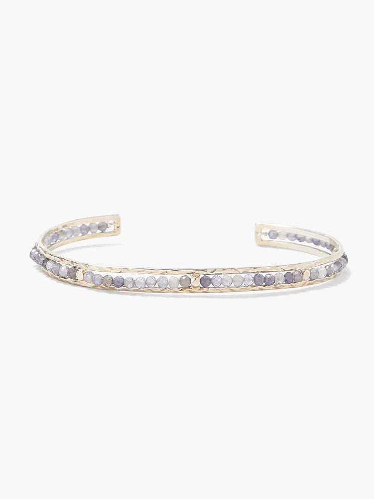 Gold cuff bracelet with row of small, light purple and gray stones.