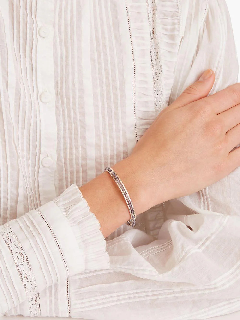 Silver bangle bracelet with small, dark purple stones.