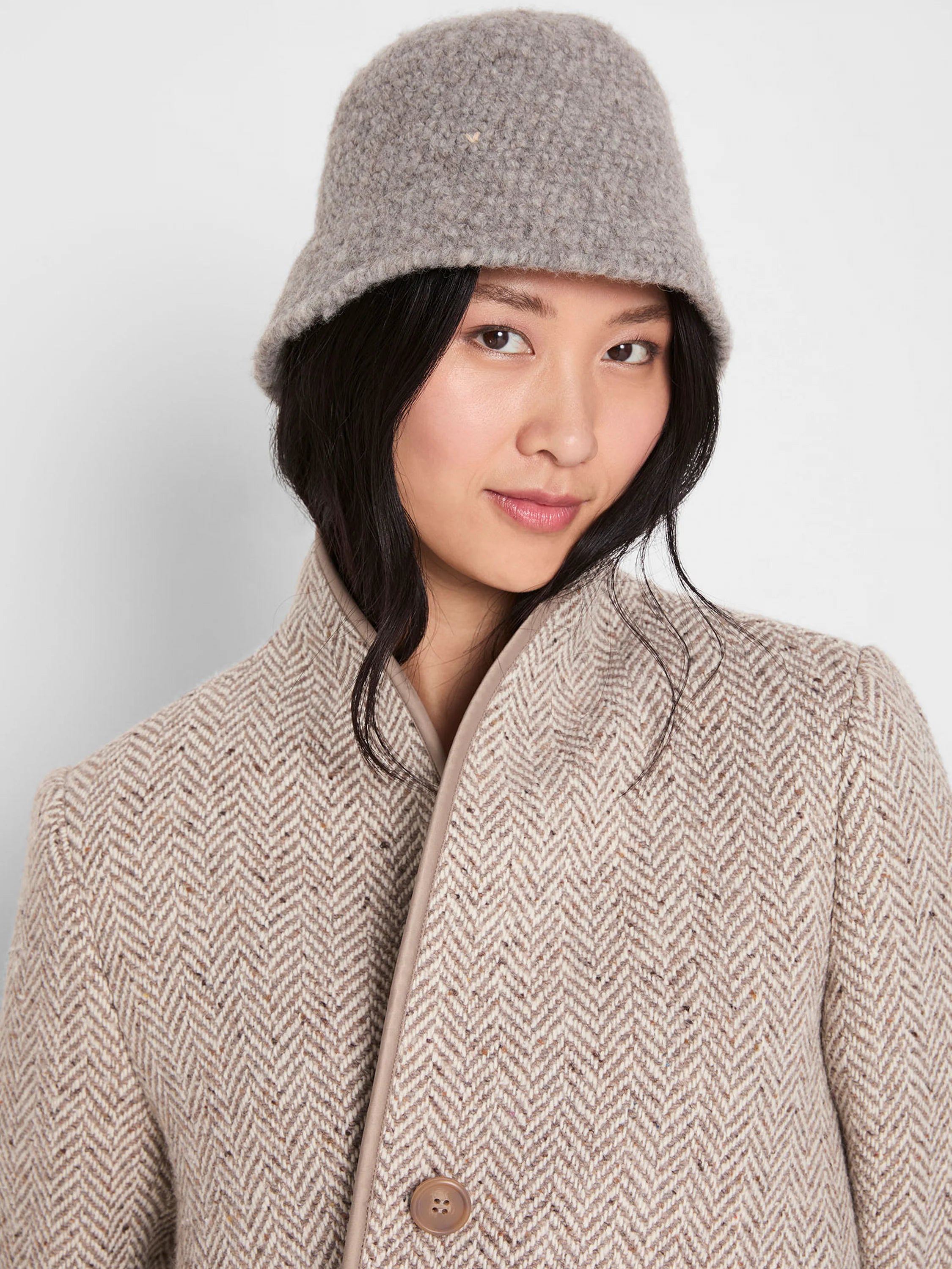 Light grey bucket hat with a chunky, textured wool-like surface, worn by a model.