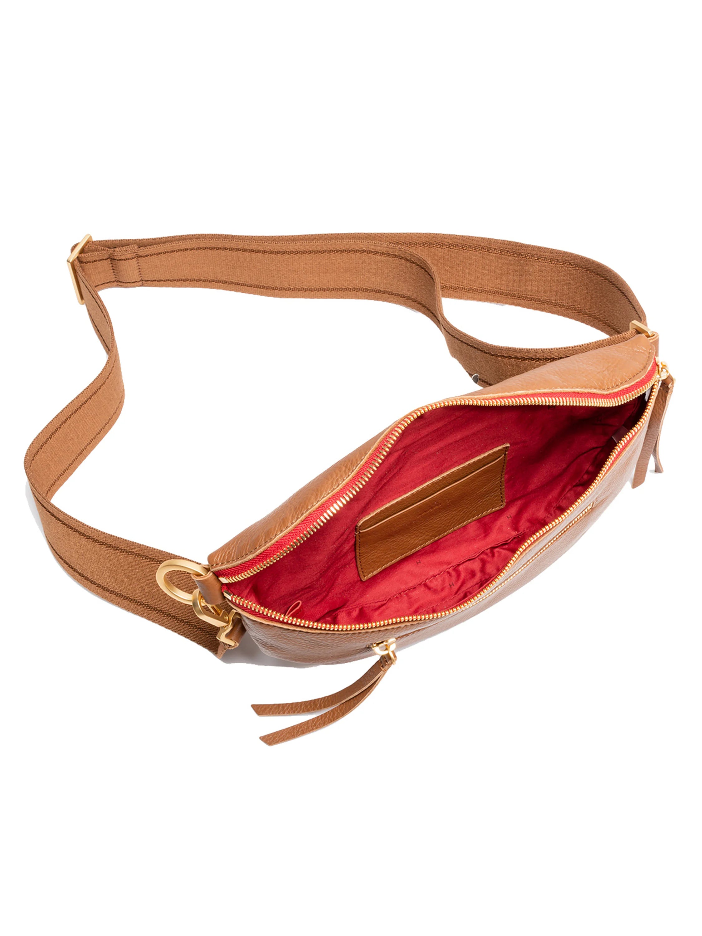 Tan pebbled leather crossbody bag, open to show red lining, gold zippers, internal pocket, and brown fabric strap.