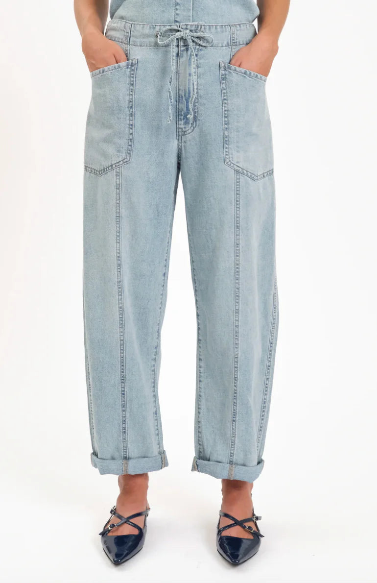 Light wash barrel leg jeans with a drawstring waist, large front patch pockets, front vertical seams, and cuffed hems.