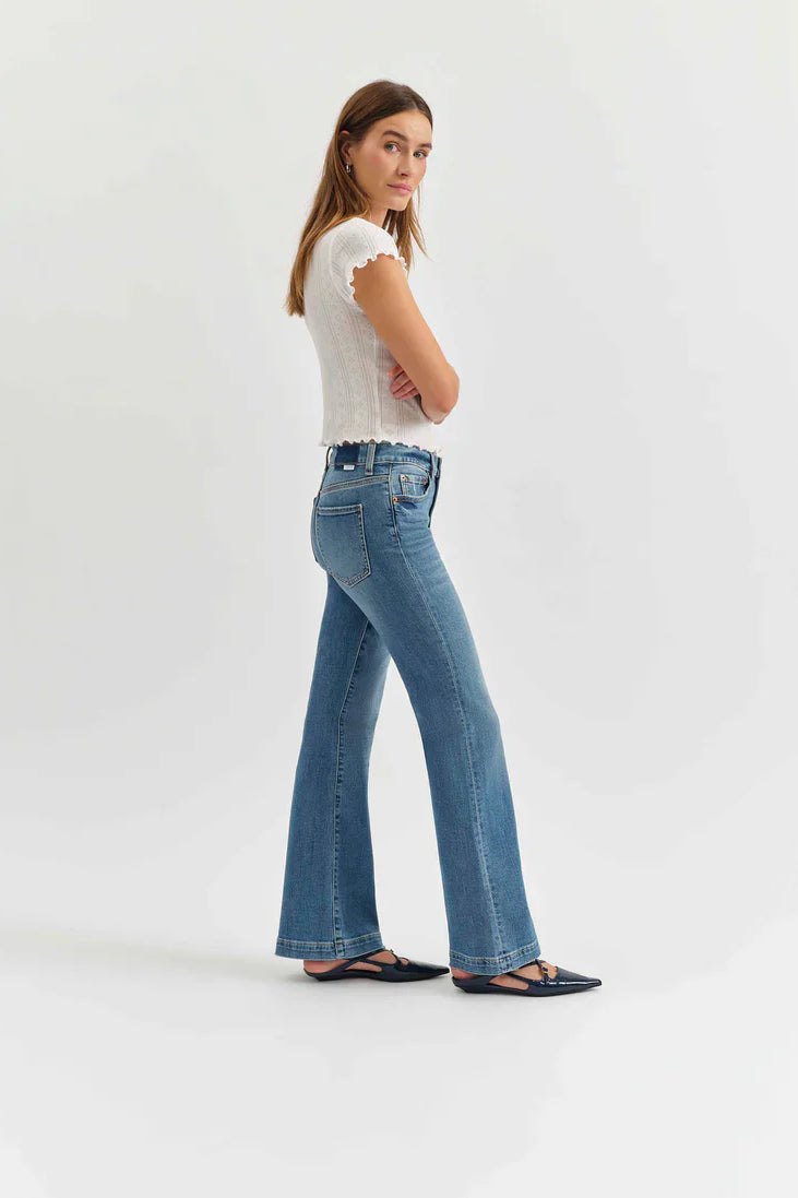 Medium blue mid-rise flare jeans, modeled from hip to floor, showing standard pockets and belt loops.