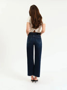 Dark wash high-rise wide ankle jeans with back pockets and frayed hem, viewed from behind.