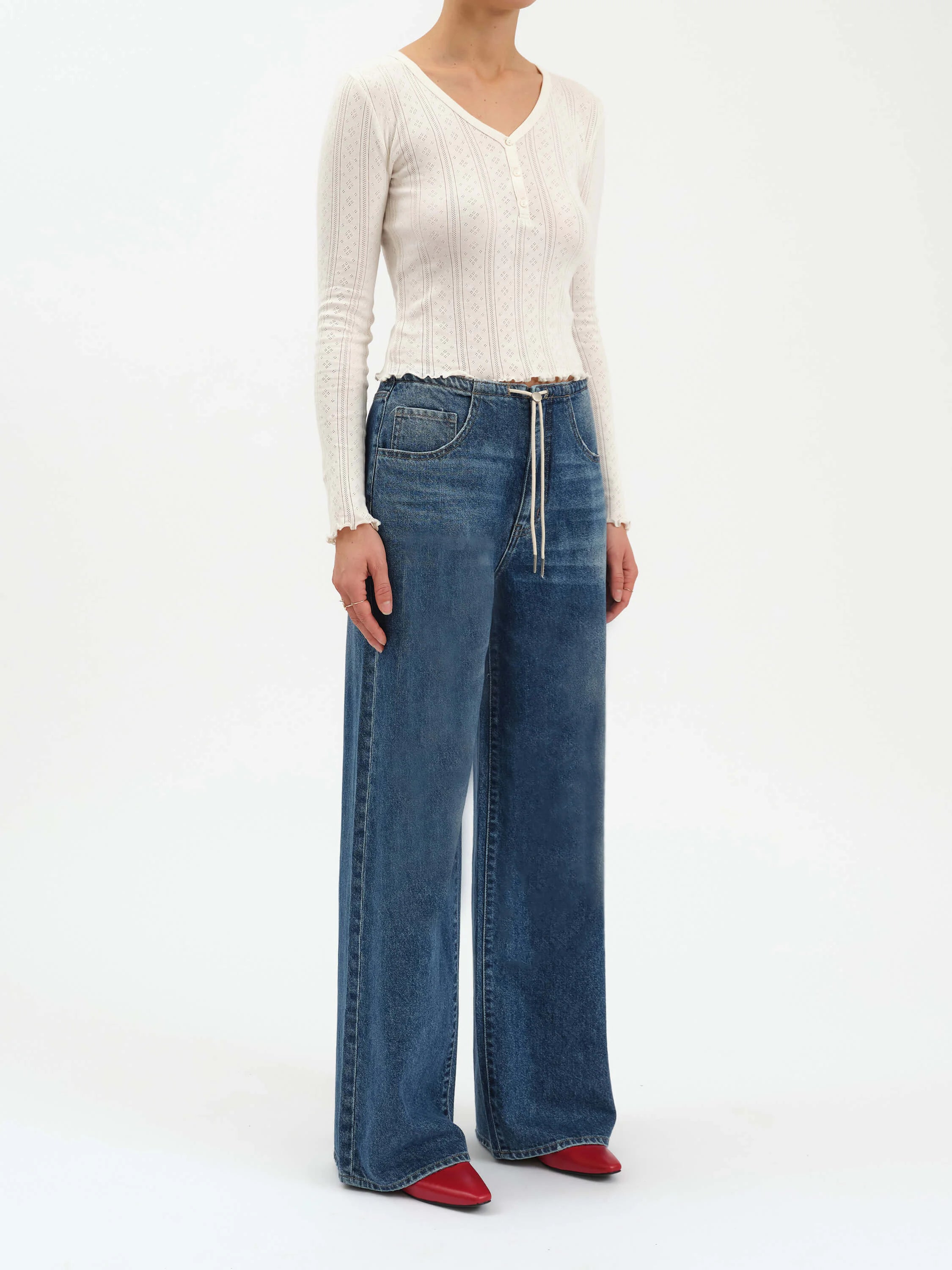 Medium blue wide leg jeans with an elastic drawstring waist, white cord, light wash fading, and front pockets.