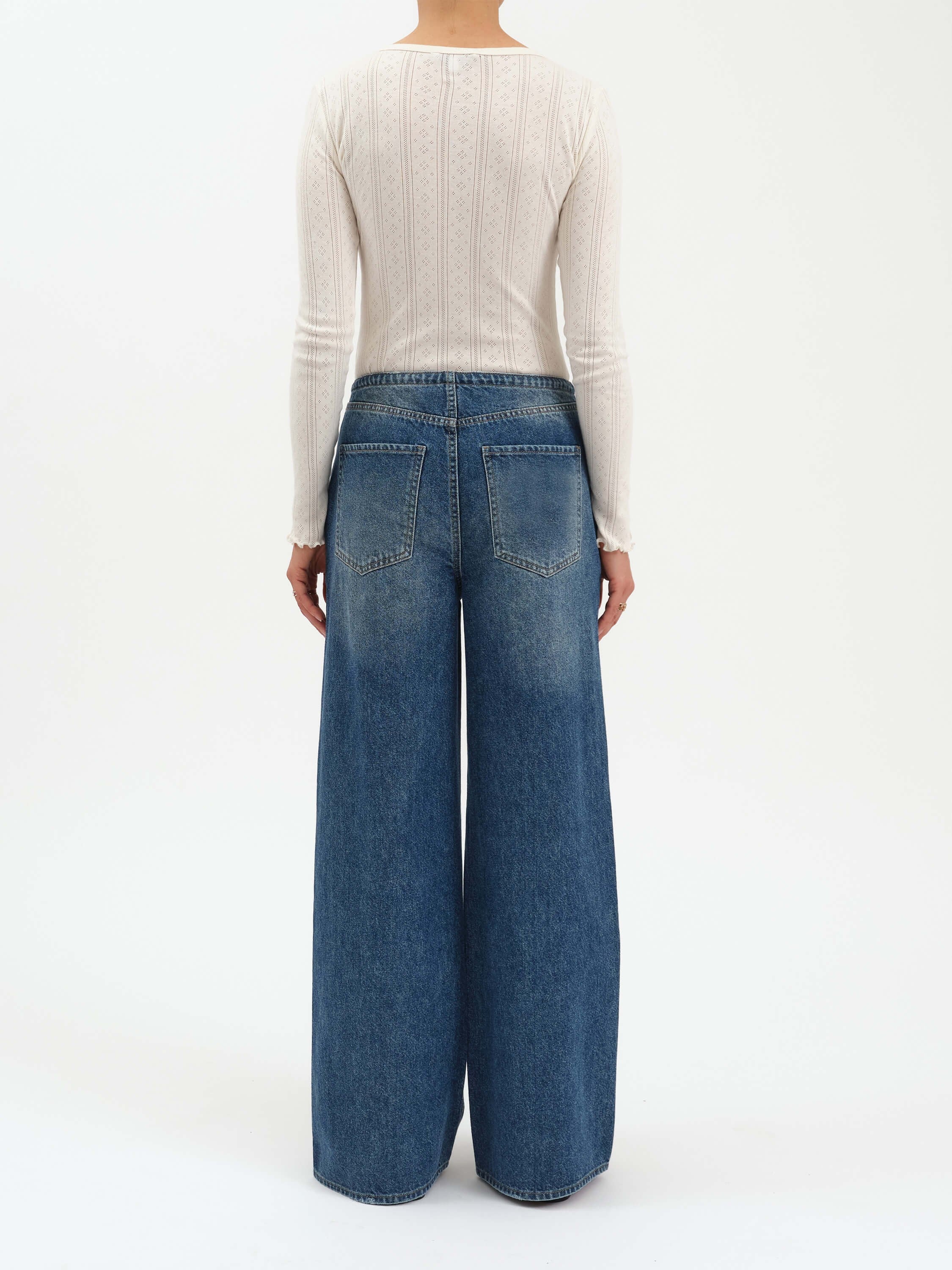 Medium blue, mid-rise wide leg jeans, shown from the back with fading and two pockets.