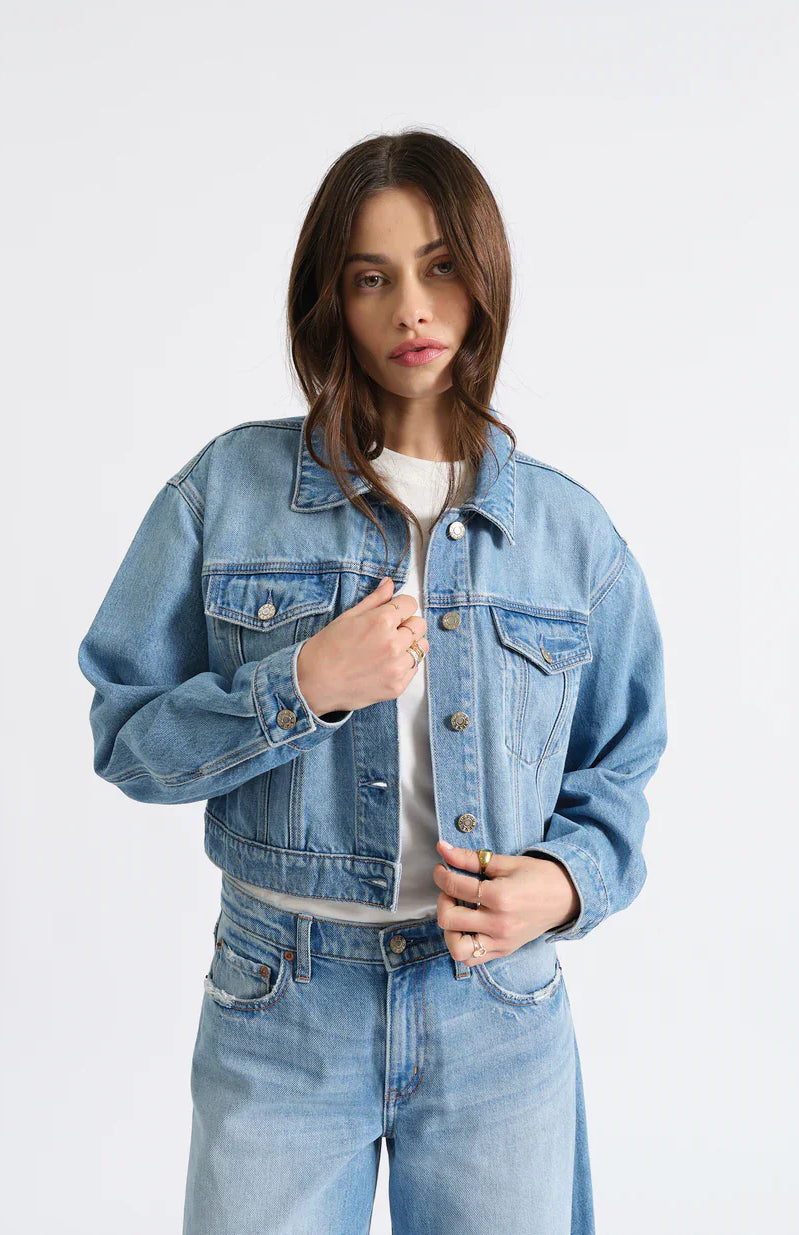 Light blue cropped jean jacket with silver buttons, a collar, and two flap chest pockets.