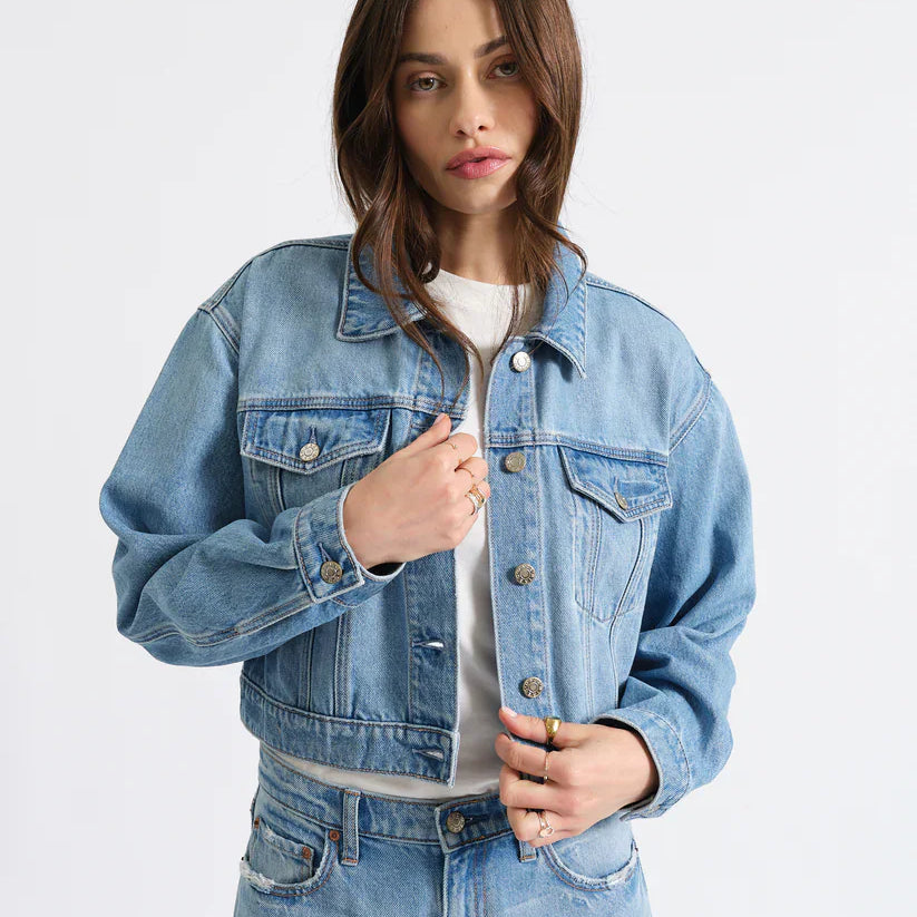 Light blue cropped jean jacket with silver buttons, a collar, and two flap chest pockets.