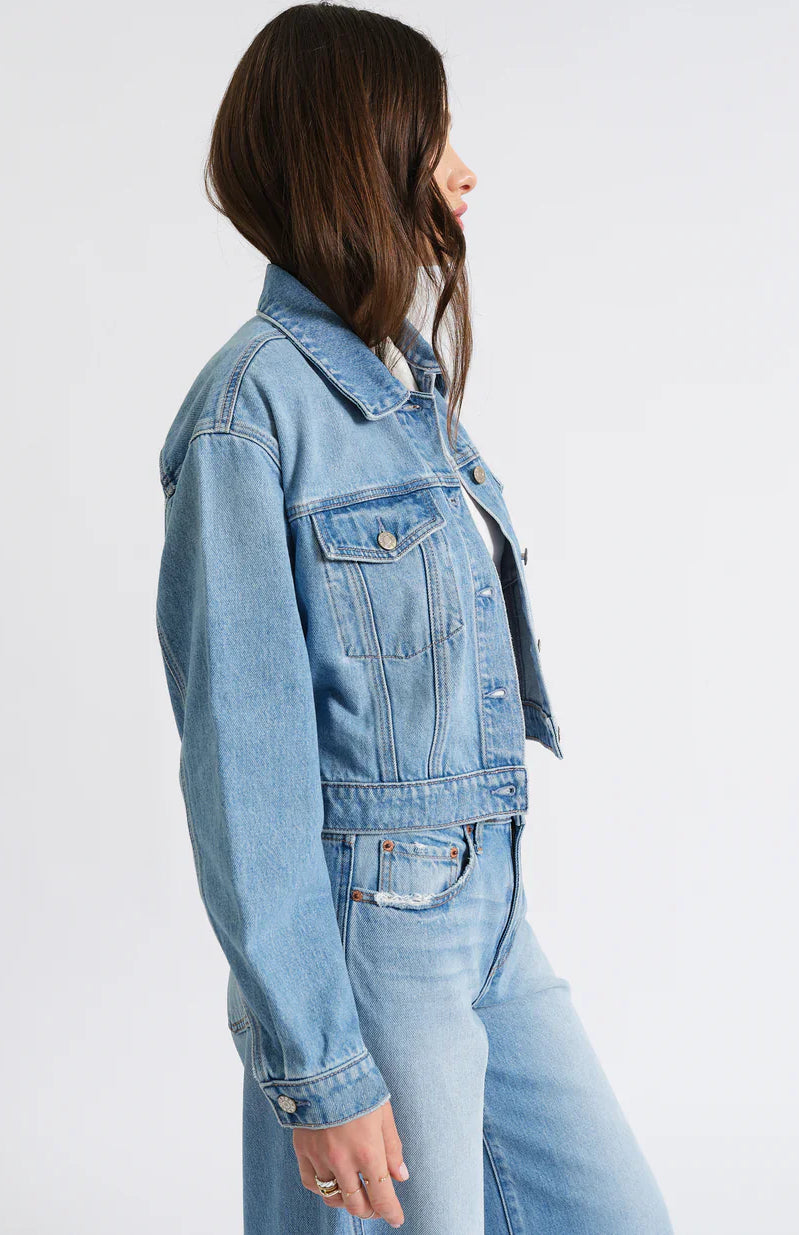 Light blue, cropped denim jacket with classic collar, button-front, and two chest pockets on a model.