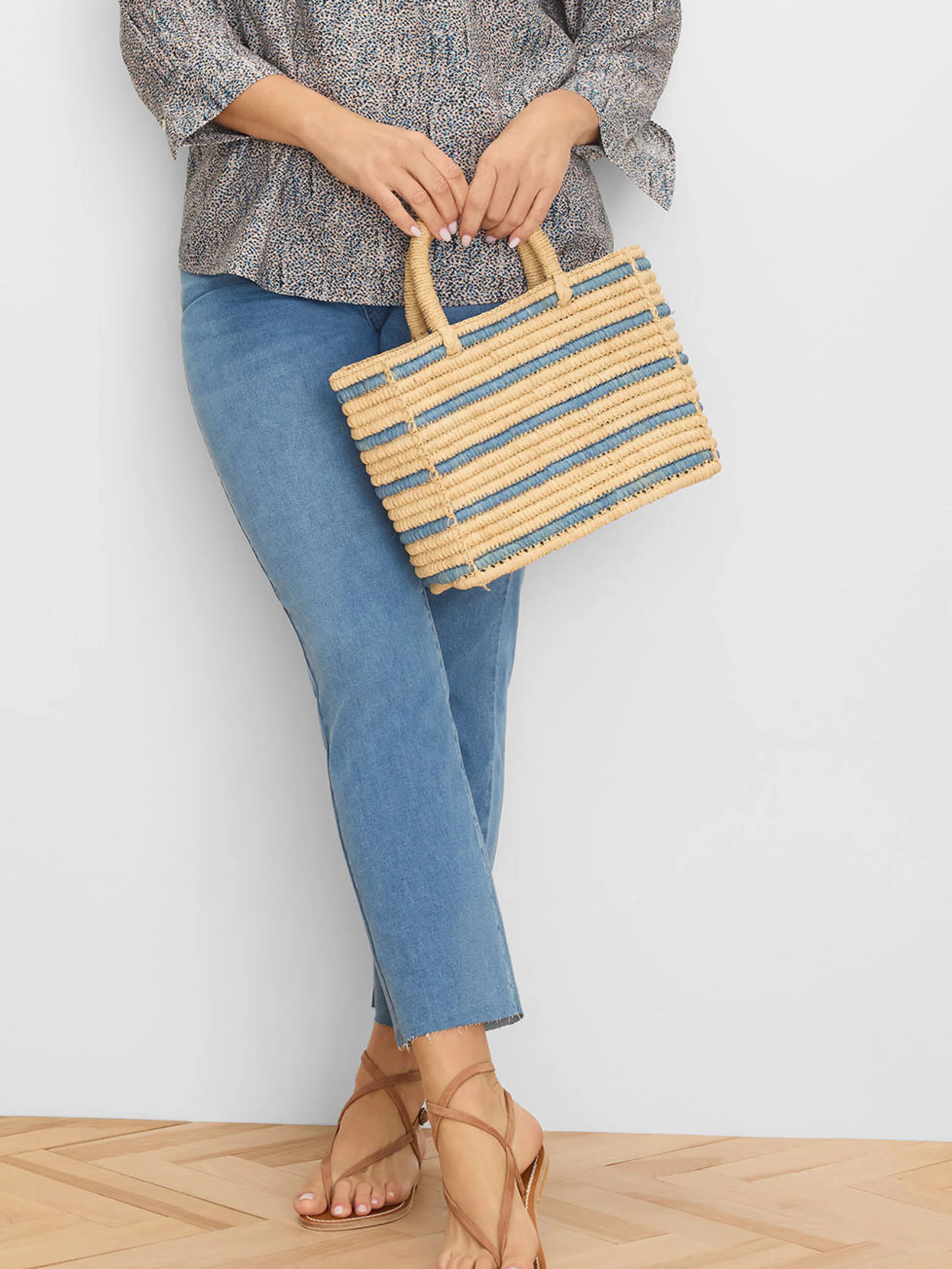 Rectangular woven straw bag, natural beige with horizontal muted blue stripes. Short straw handles.