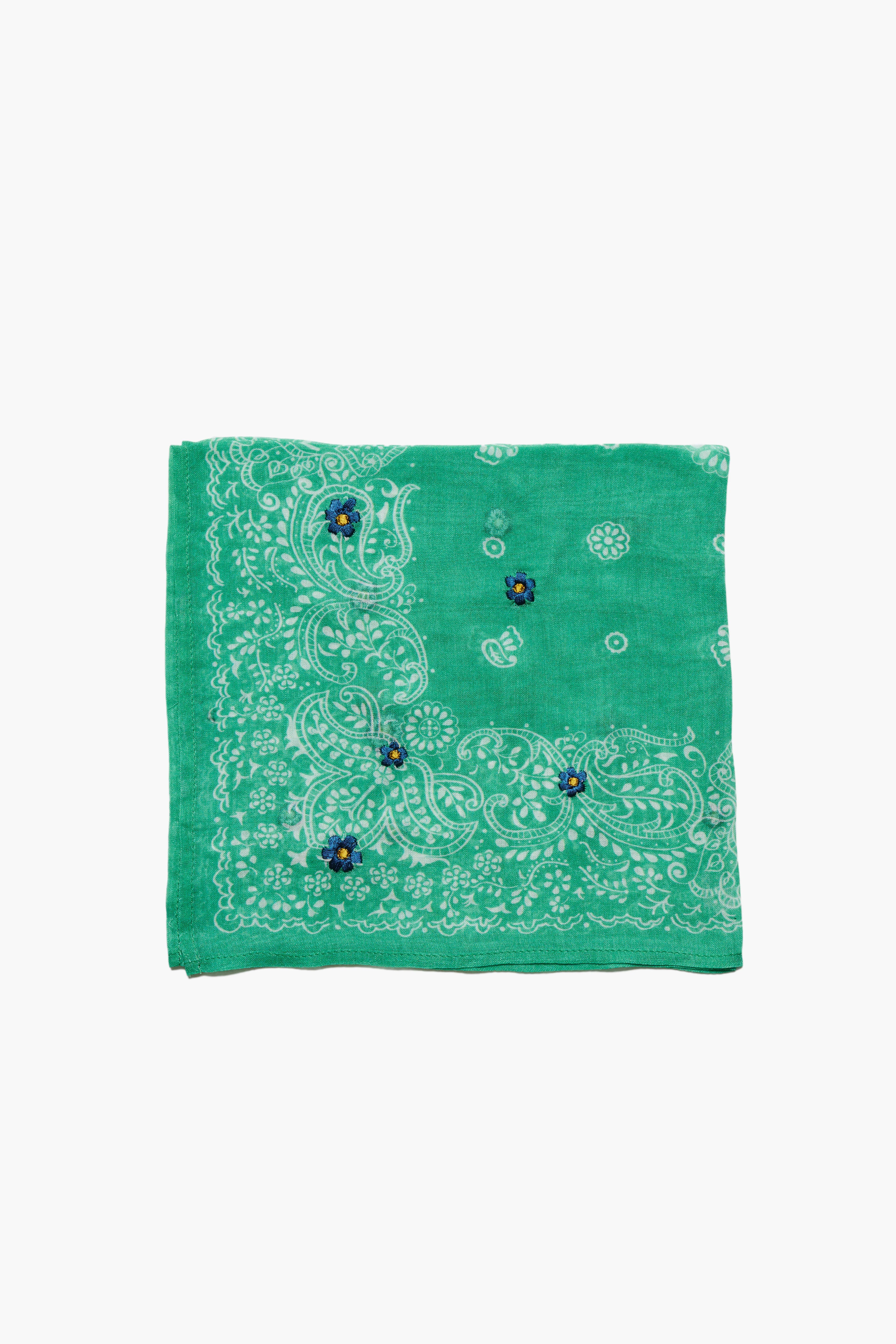 Folded green bandana with white paisley print and three small blue embroidered flowers with yellow centers.