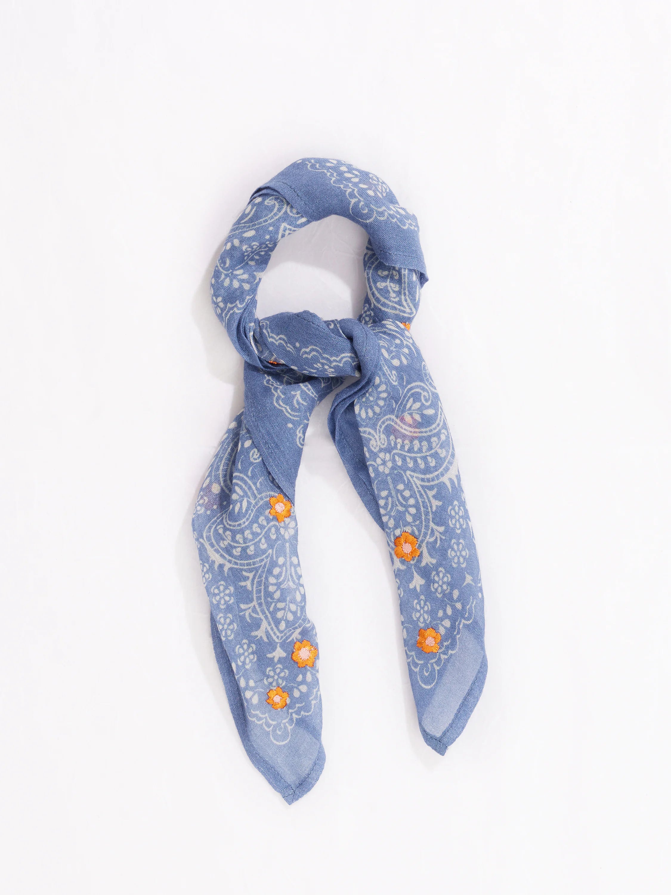 Blue bandana with white paisley and orange floral embroidery. Folded.