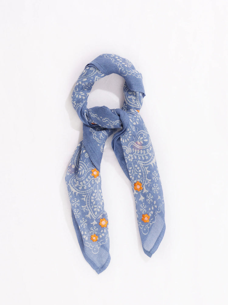 Blue bandana with white paisley and orange floral embroidery. Folded.